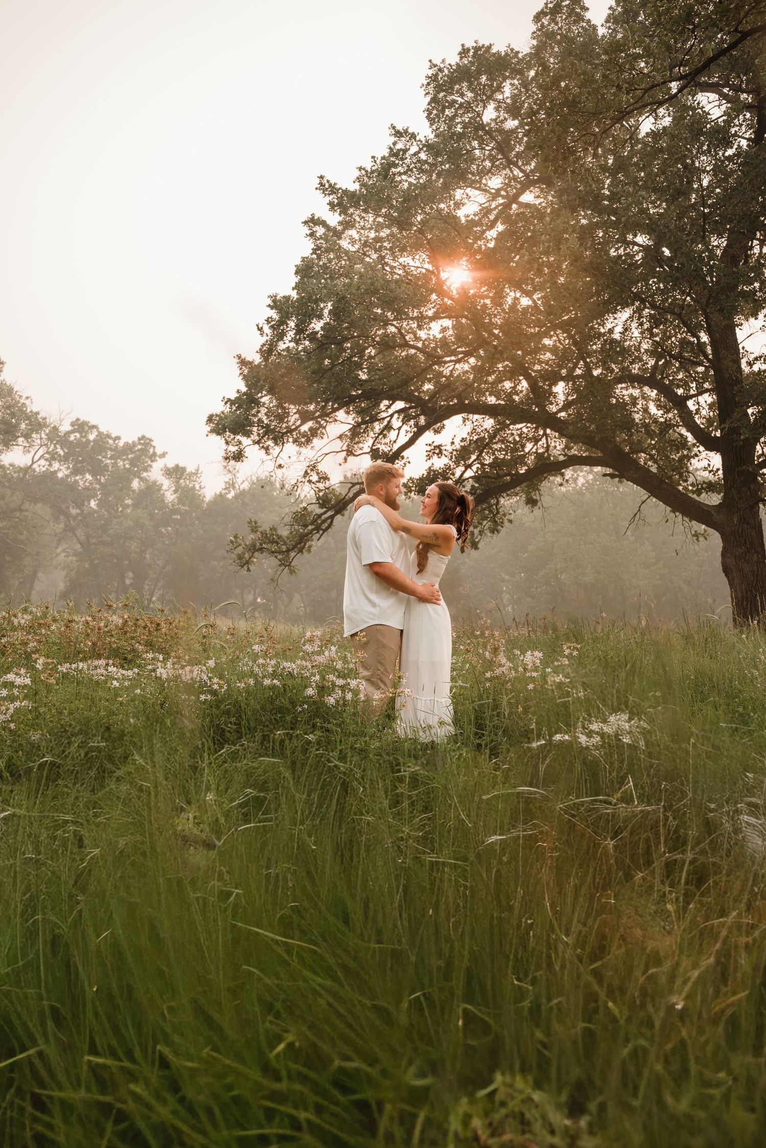Couple cuddling together beneath tall trees in Elk River Minnesota