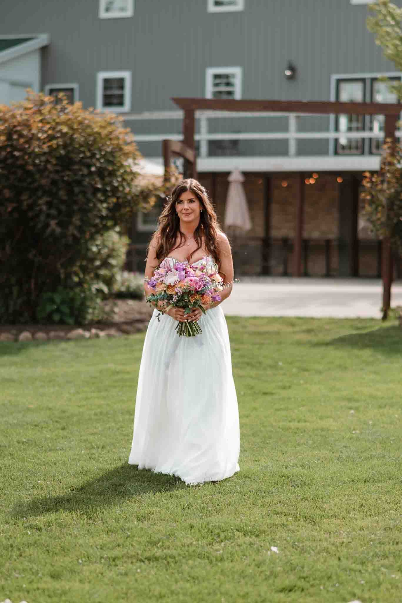 Bride walking down the aisle toward her partner during the wedding ceremony at Harvest Moon Pond