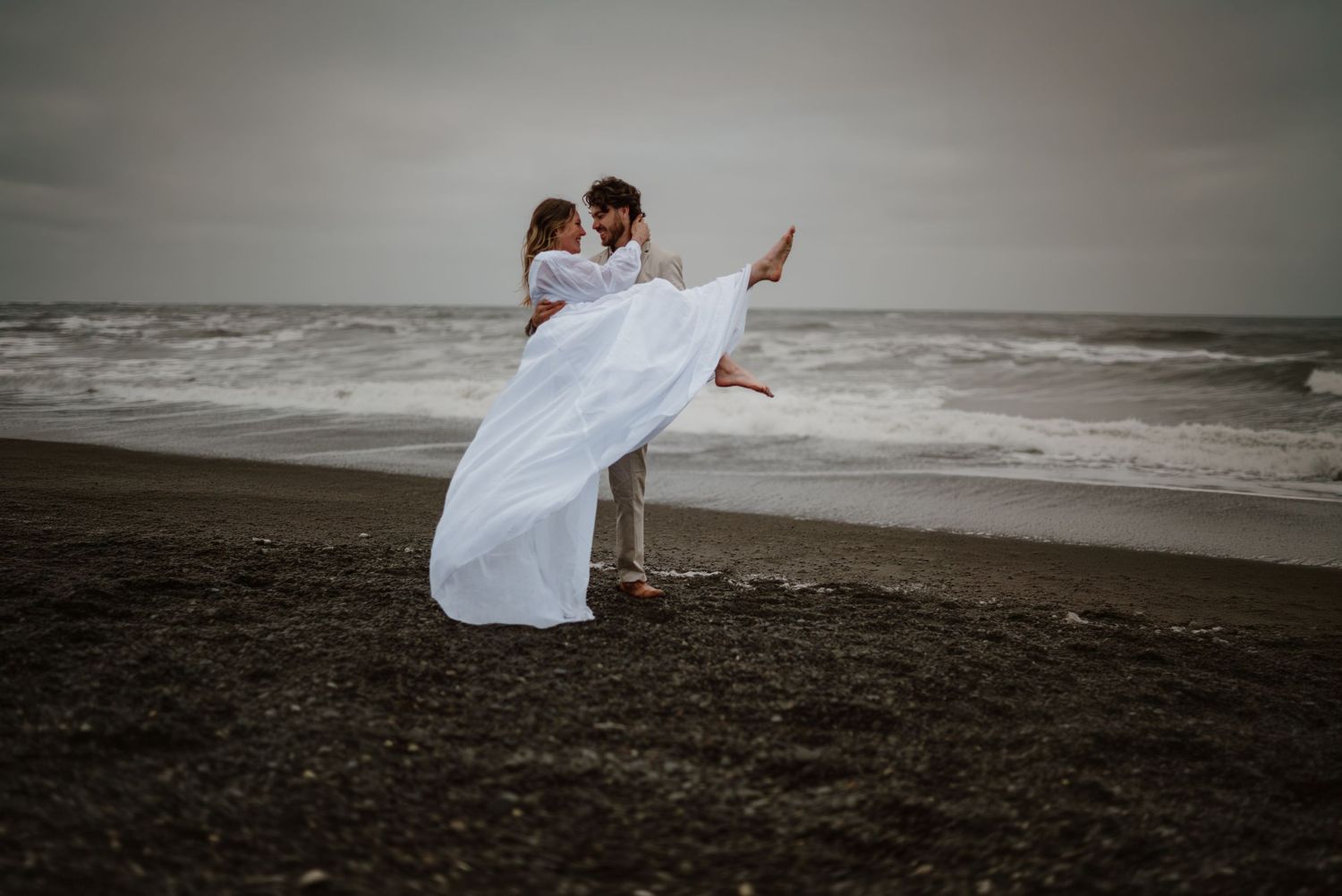 Groom lifting and spinning the bride around on the beach at Rialto Beach in Washington