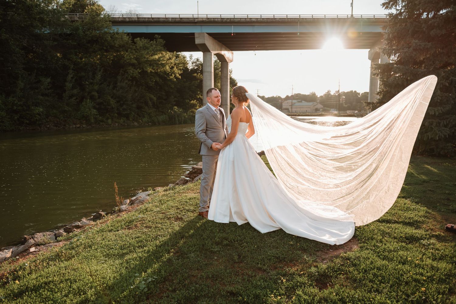 bride with her veil blowing in the breeze holding hands with groom during golden hour photos at West Edison Rivery