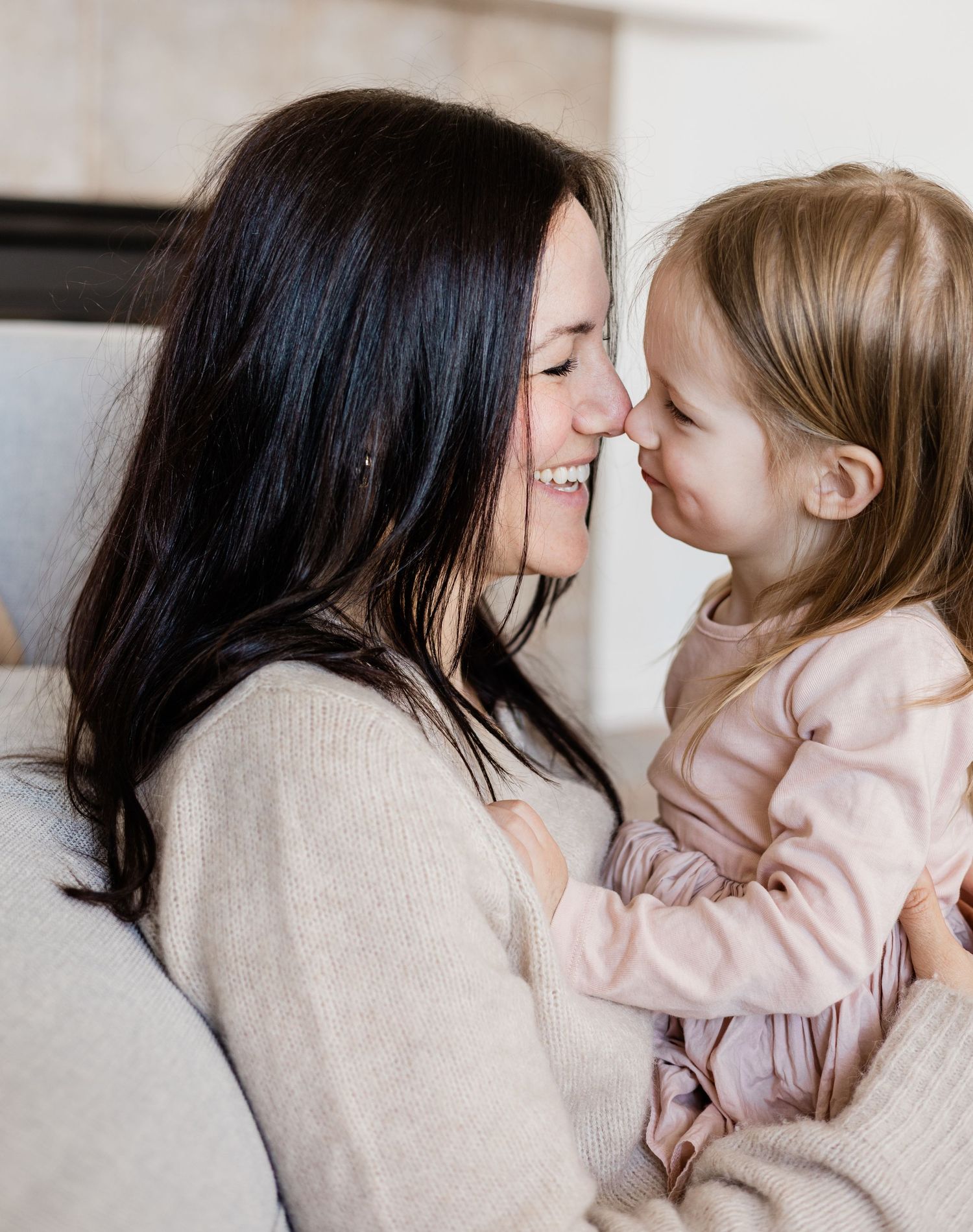 Loving mother and toddler daughter sharing a tender nose-to-nose moment, smiling warmly at each other.