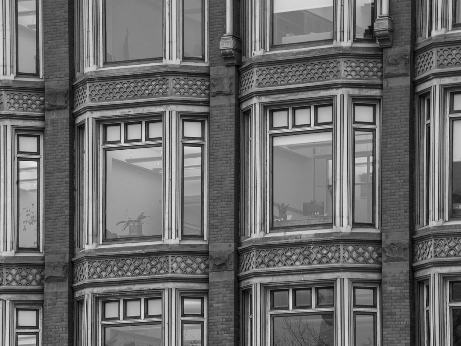 Black and white close-up of ornate Victorian red brick building facade with curved bay windows.