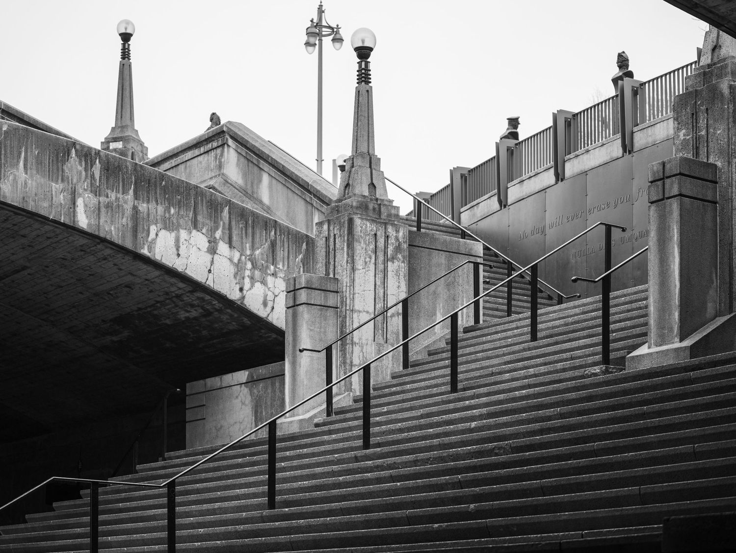Black and white urban architecture featuring stone stairs, metal railings, bridge, and Gothic church spires.