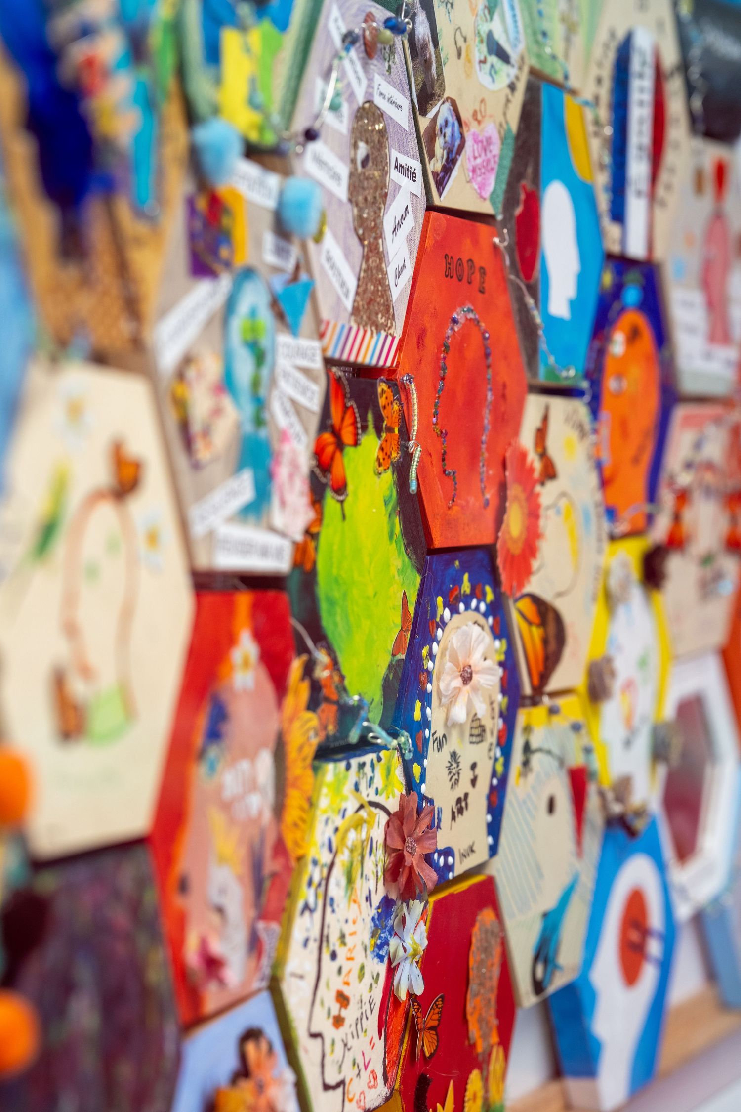 A colorful wall display of painted hexagonal tiles featuring various artistic designs and illustrations.