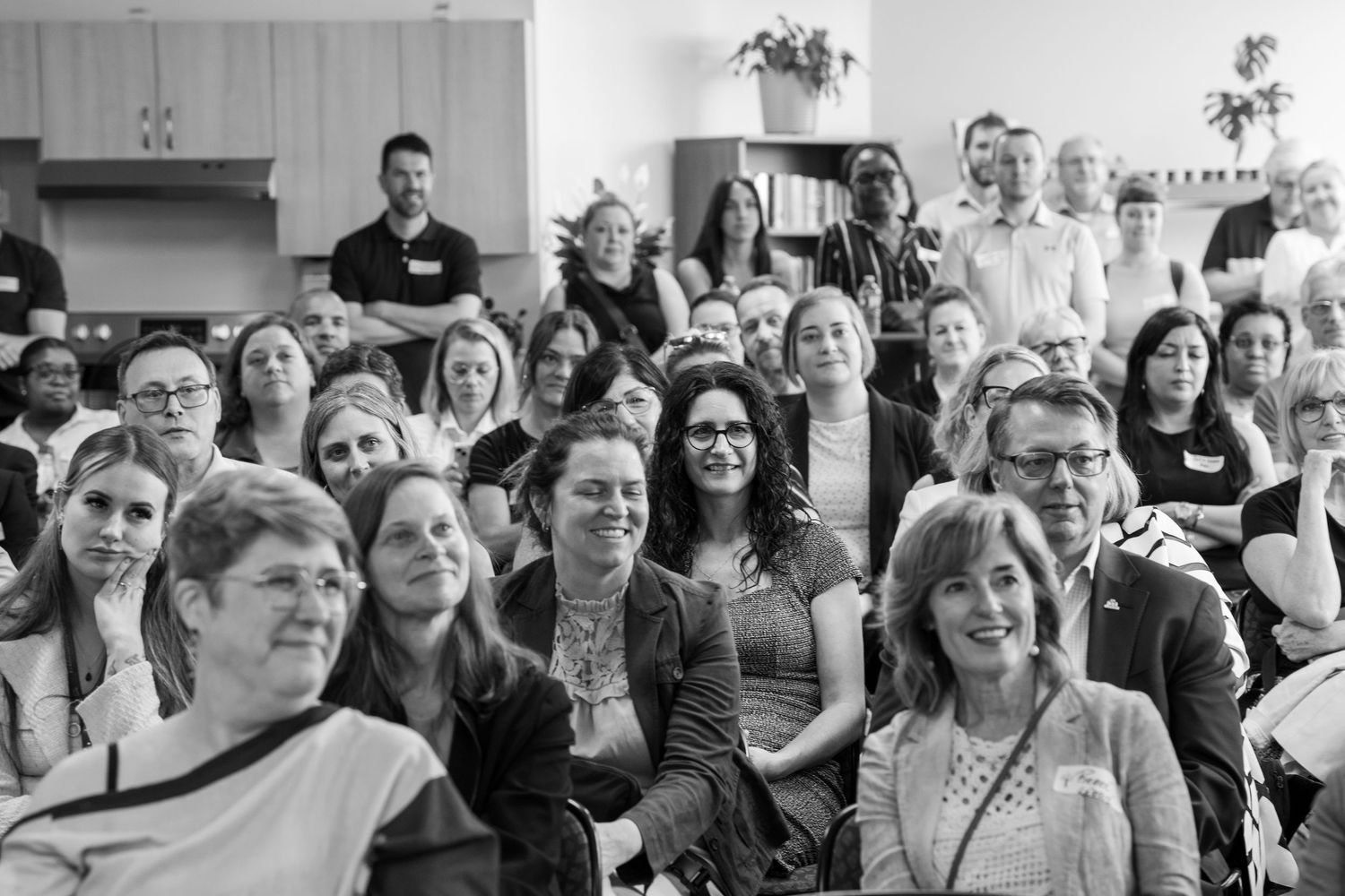 A black and white photo of a large diverse crowd of people gathered at an indoor event.