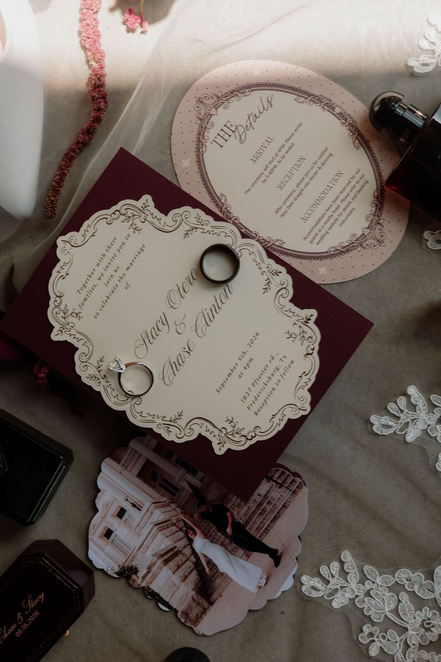 Elegant wedding invitation suite with burgundy and blush details, rings, lace, and a vintage photo on a neutral backdrop.