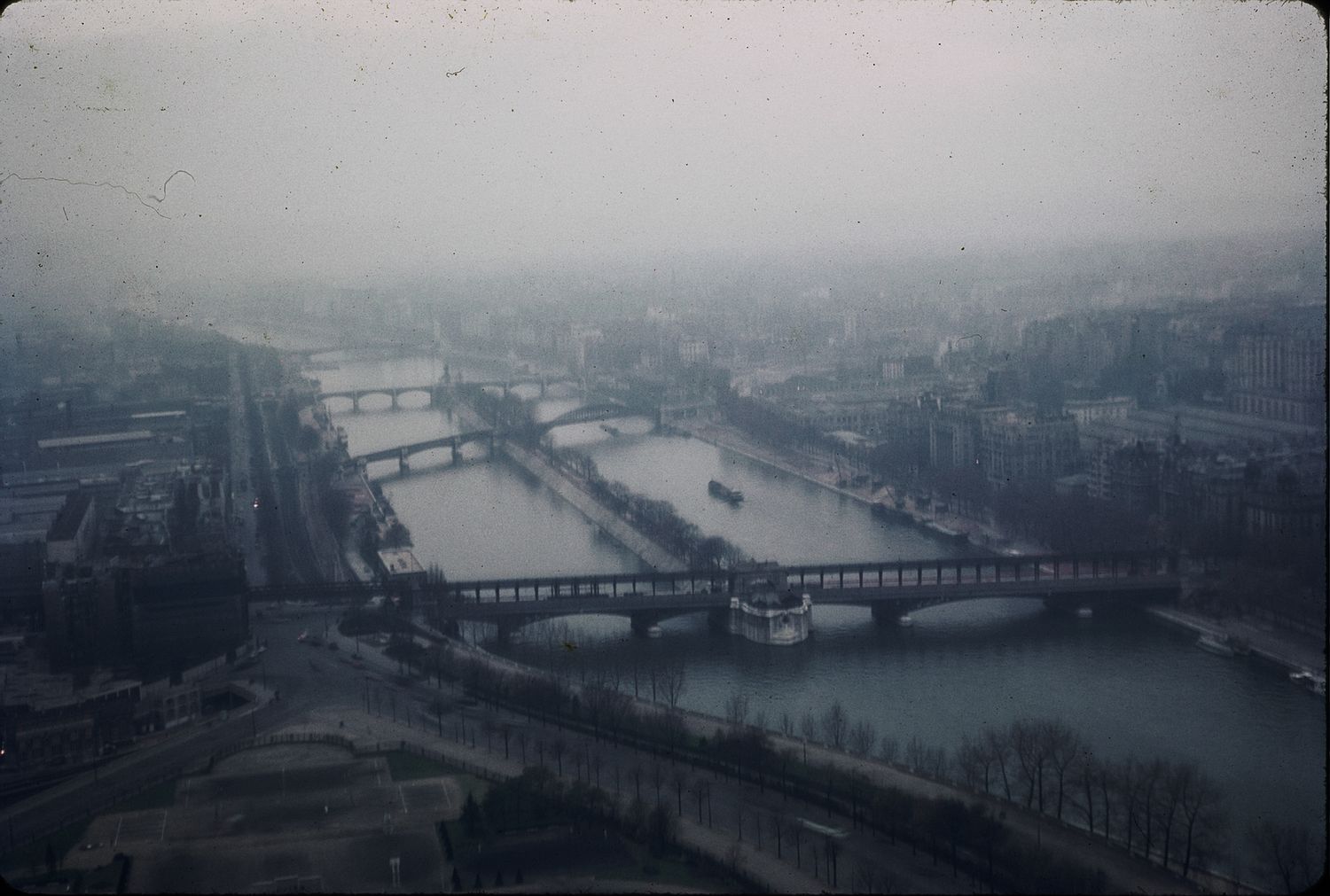 Aerial foggy view of the Seine River with multiple bridges cutting through Paris, France.