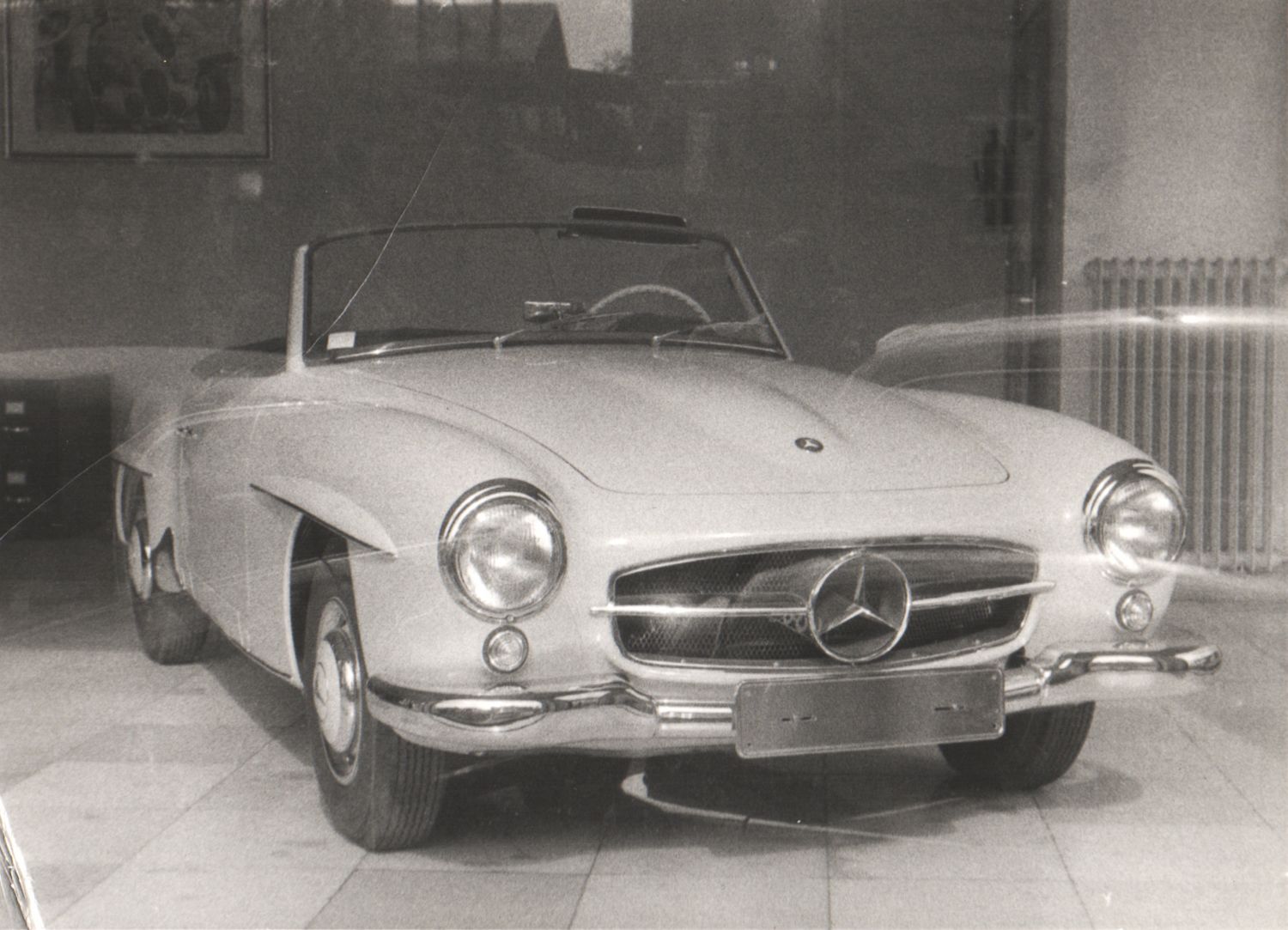Vintage Mercedes-Benz 190SL convertible sports car in black and white showroom photo.