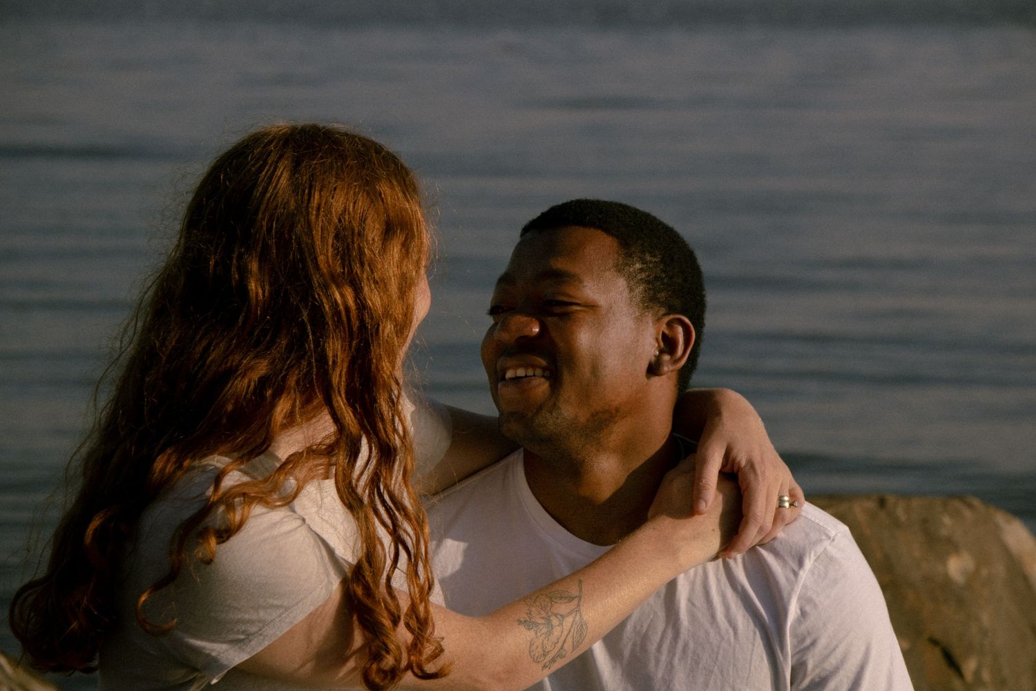 SAINT JAMES PHOTO-A smiling interracial couple shares a tender moment by Lake Erie, the woman resting her arm around the mans shoulder.
