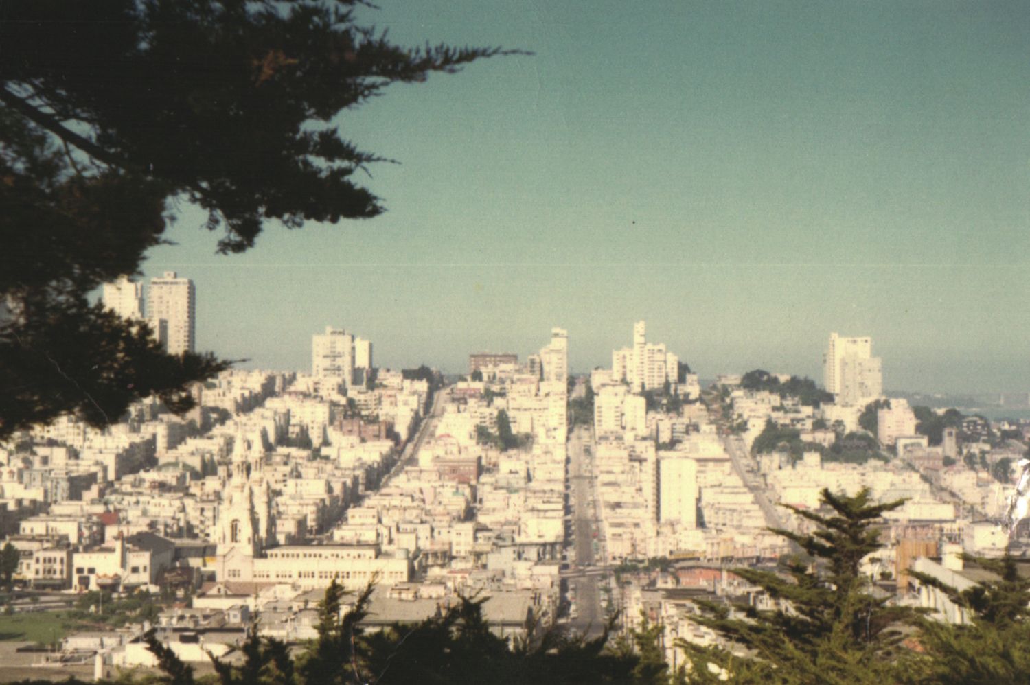 Aerial view of San Francisco cityscape with dense white buildings cascading down hilly streets on a clear day.