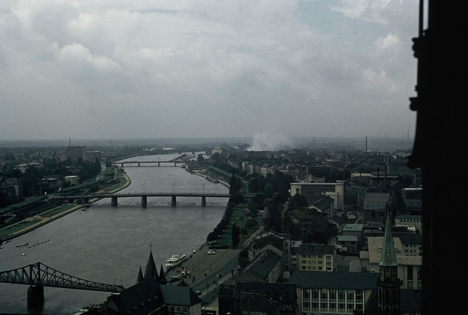 Aerial view of European city with river bridges and urban skyline under cloudy sky.