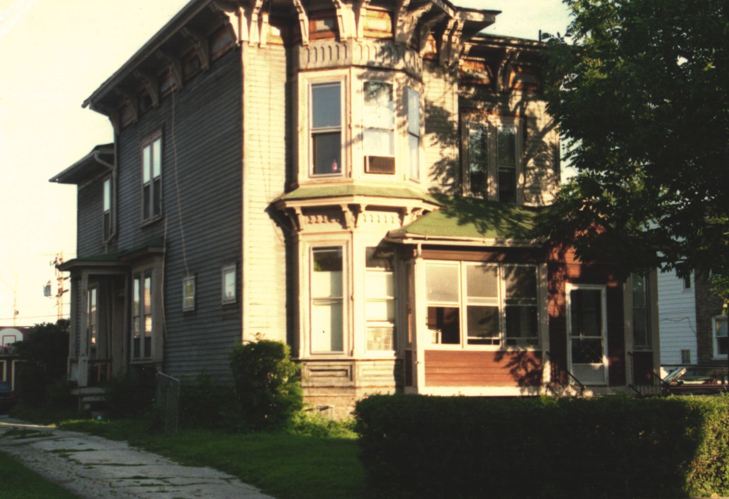 A Victorian-style two-story wooden house with ornate architectural details and bay windows on a quiet street.