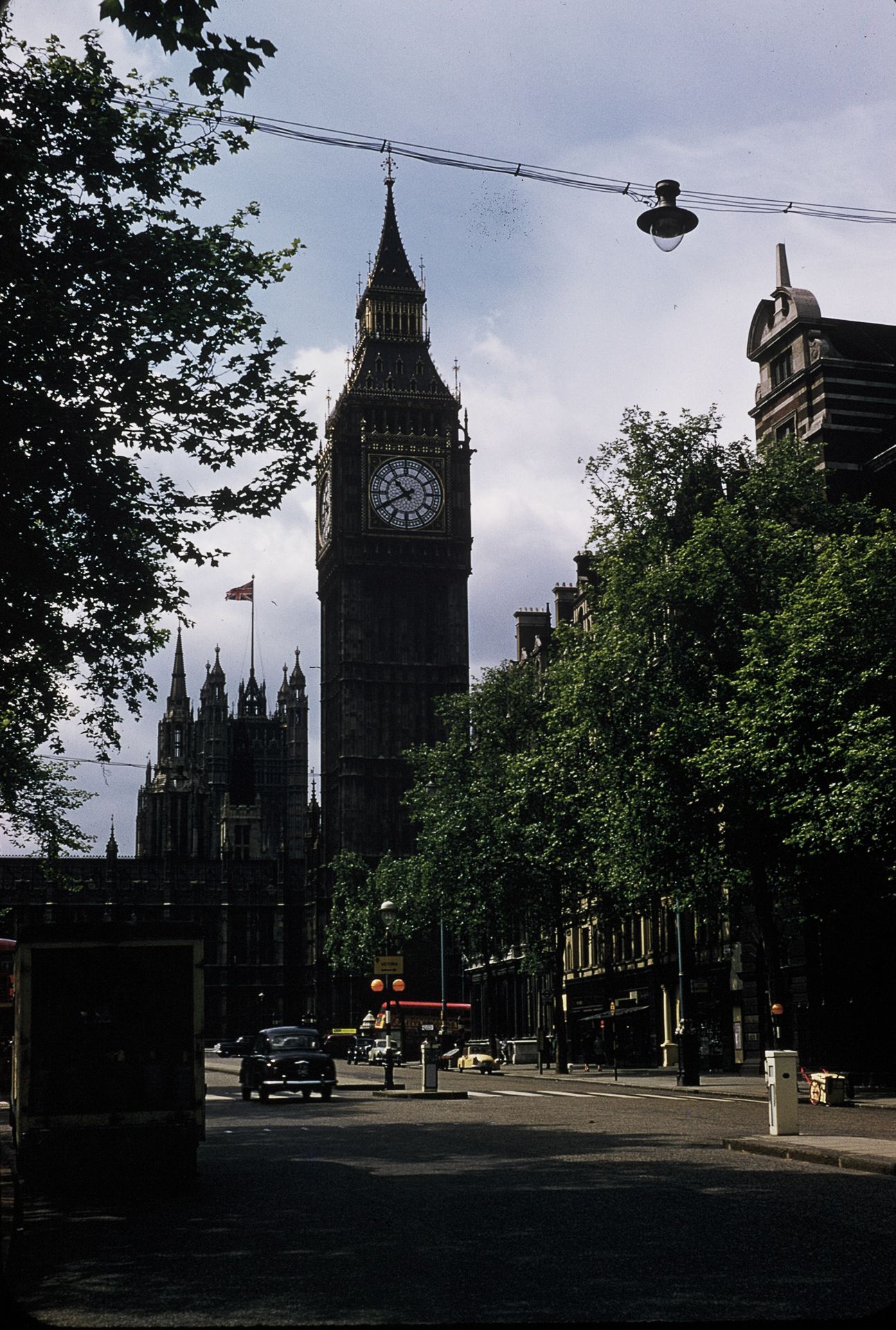 Classic view of Big Ben clock tower rising above tree-lined streets in Westminster, London, England.