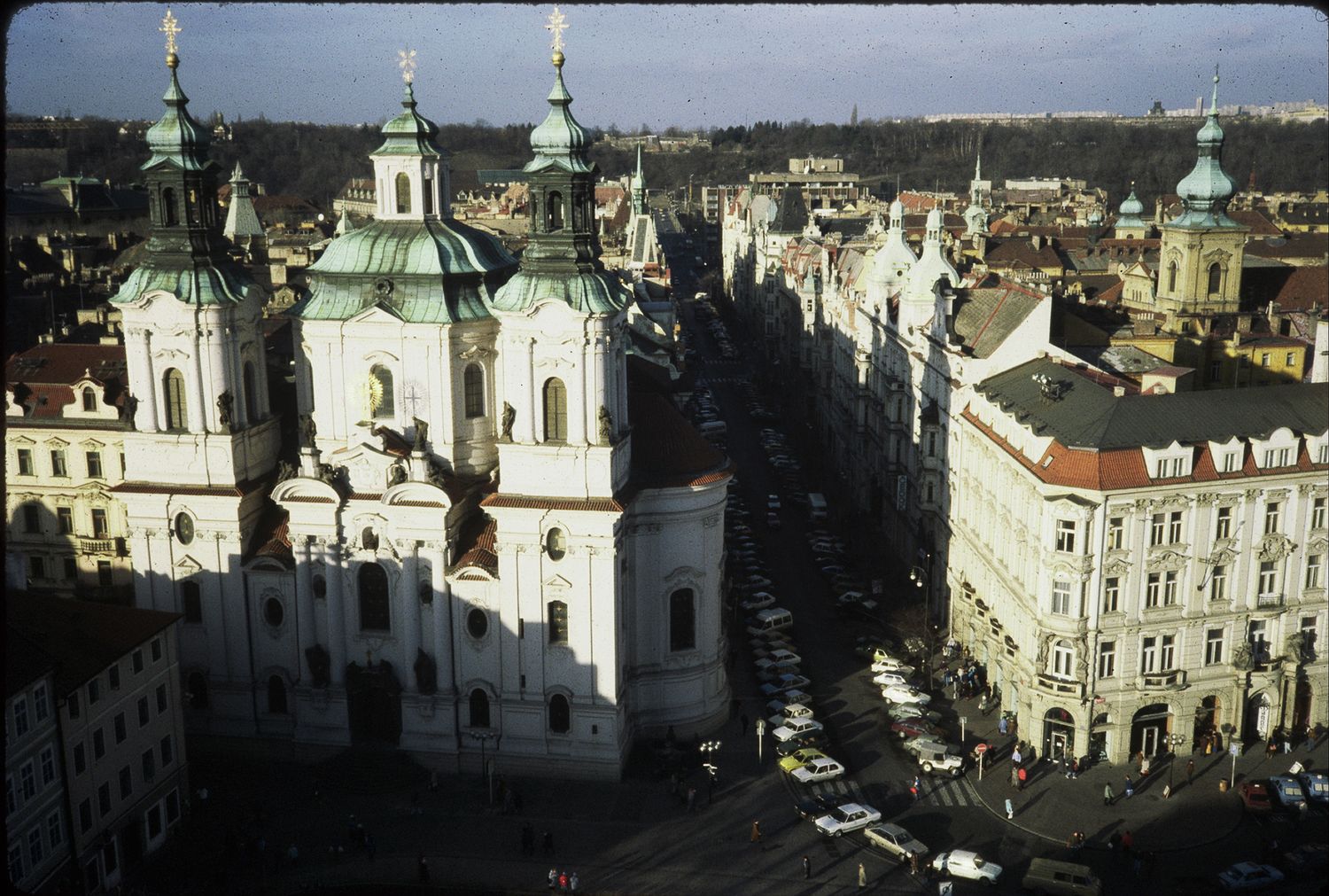 Aerial view of St. Nicholas Church baroque architecture dominating Prague Old Town Square with city streets below.