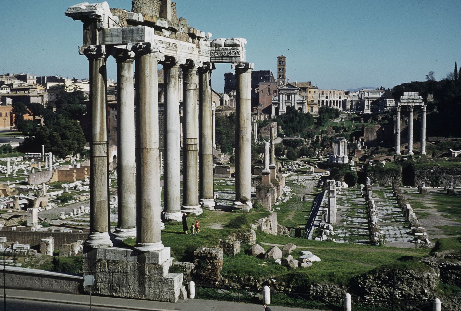 Ancient Roman Forum ruins with tall columns standing against a cityscape in Rome, Italy.