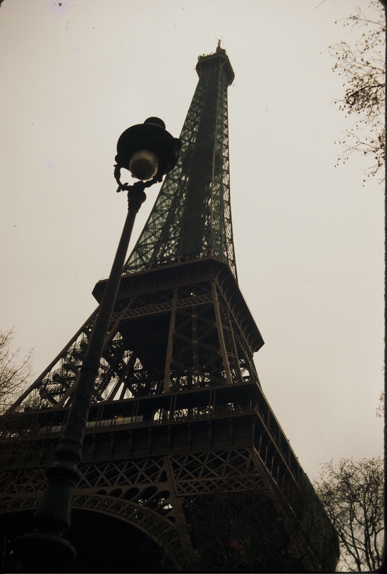 Low-angle view of the iconic Eiffel Tower in Paris with a vintage street lamp in the foreground.