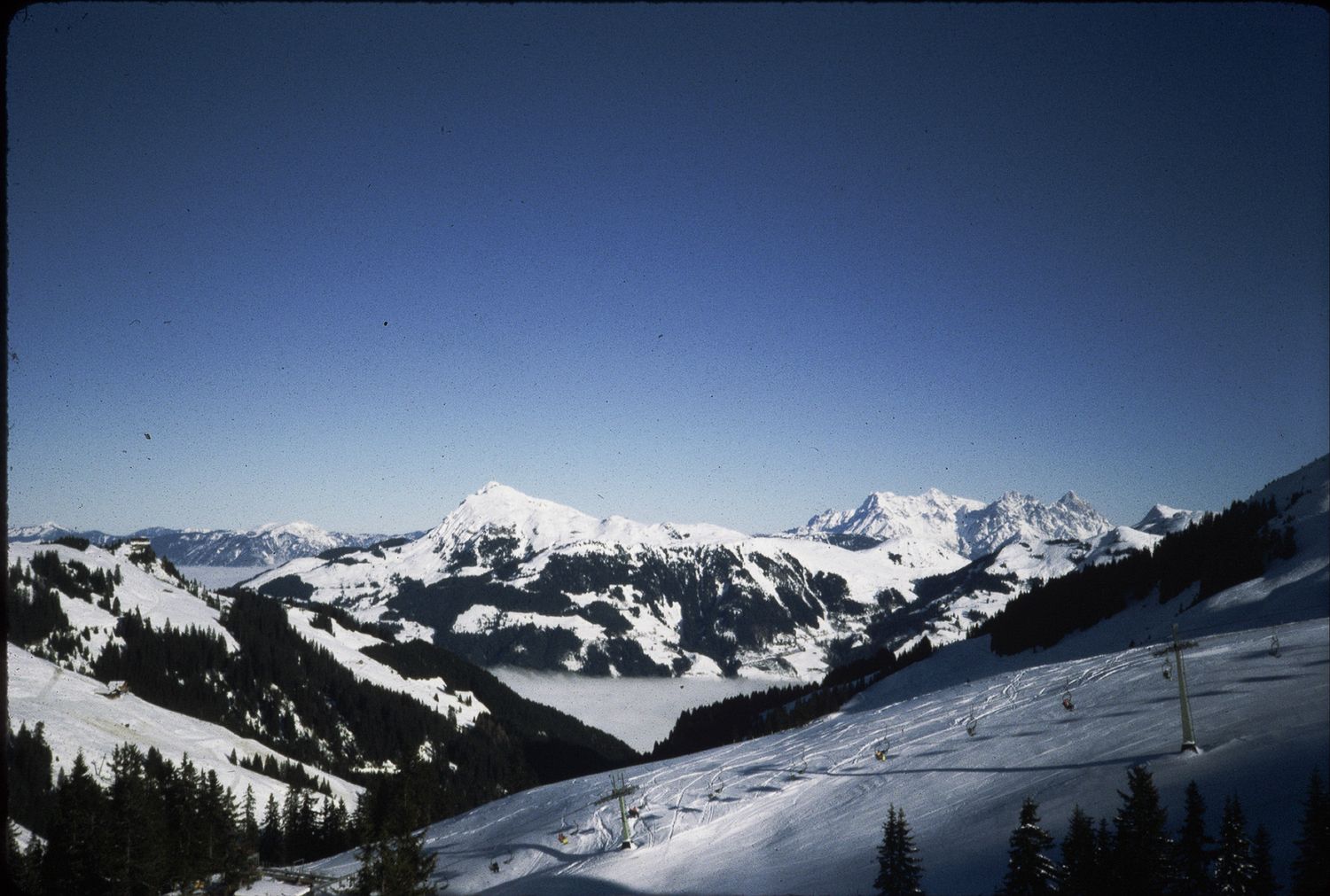 Panoramic view of snow-covered Alps mountains under a clear blue sky in winter.