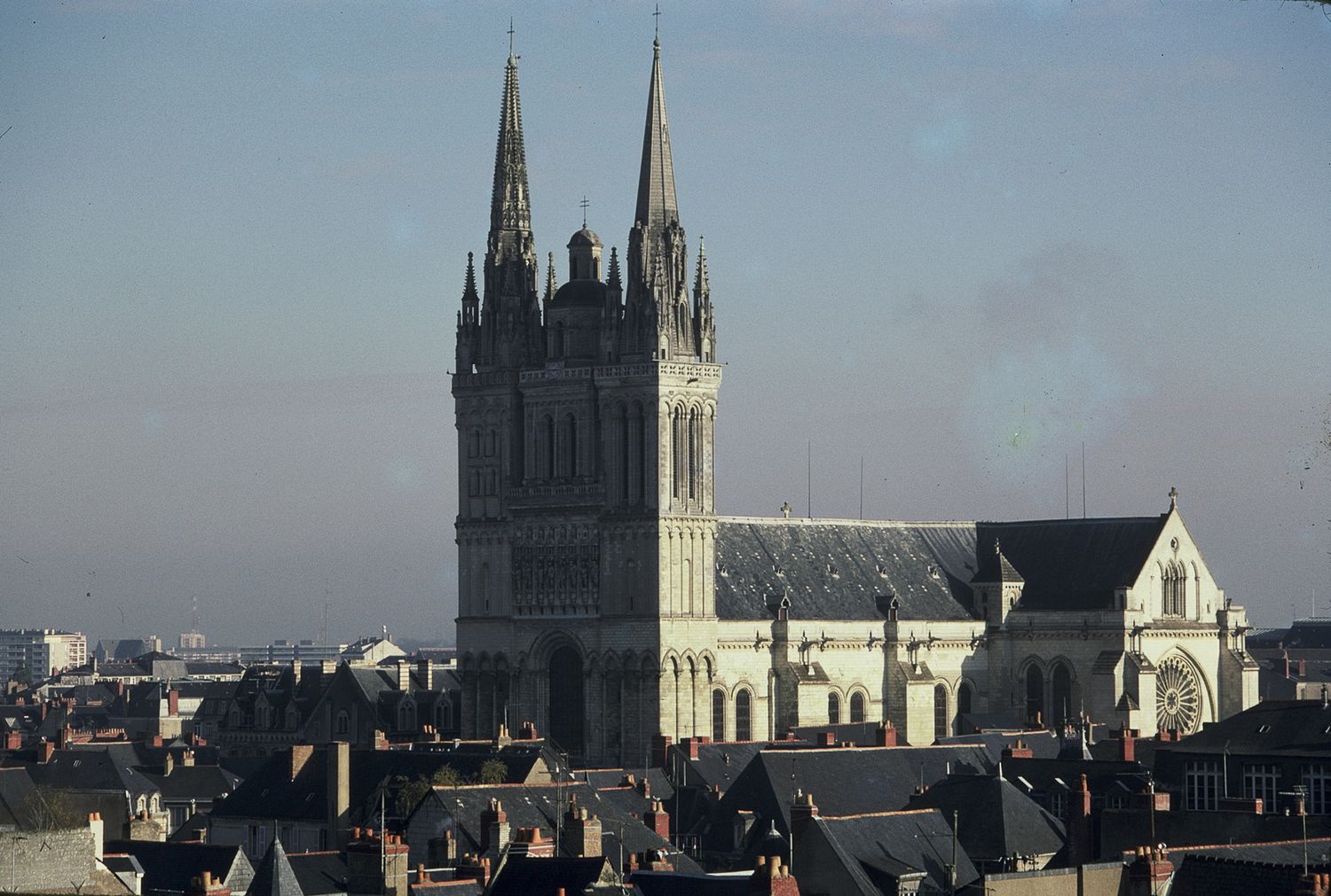 Gothic cathedral with twin spires rising above rooftops in a historic European city skyline.