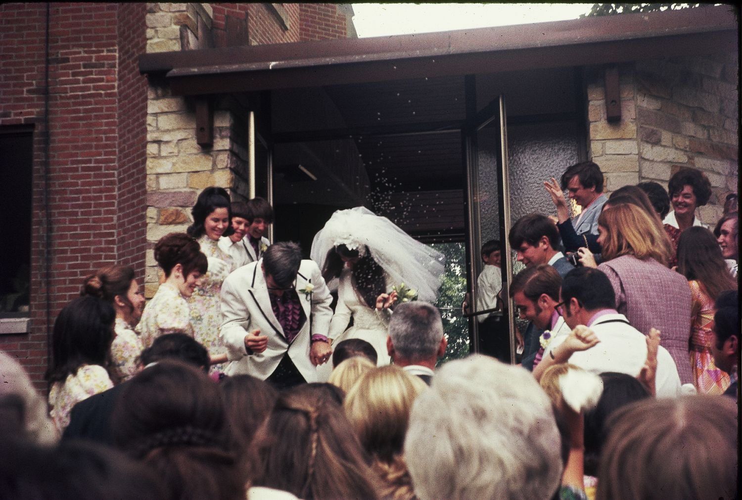 Wedding couple exits church surrounded by guests throwing confetti in a joyful celebration.