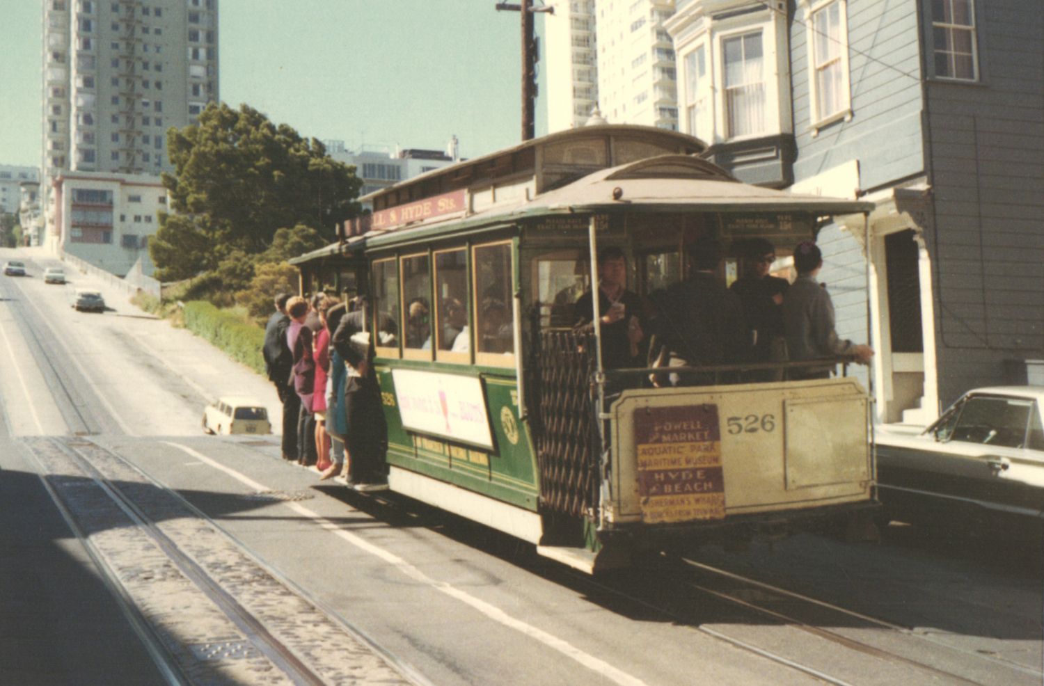 San Francisco cable car #526 picking up passengers on a steep city street hill.