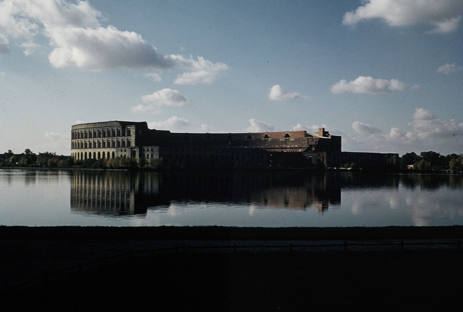 Historic stone fort reflected in calm water at dusk under a partly cloudy sky.
