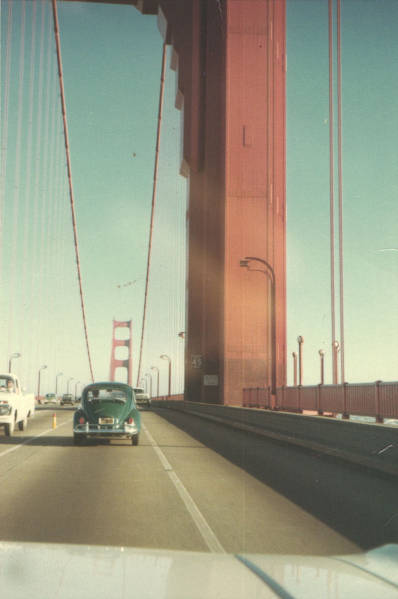 Vintage cars driving across the iconic Golden Gate Bridge in San Francisco on a clear sunny day.