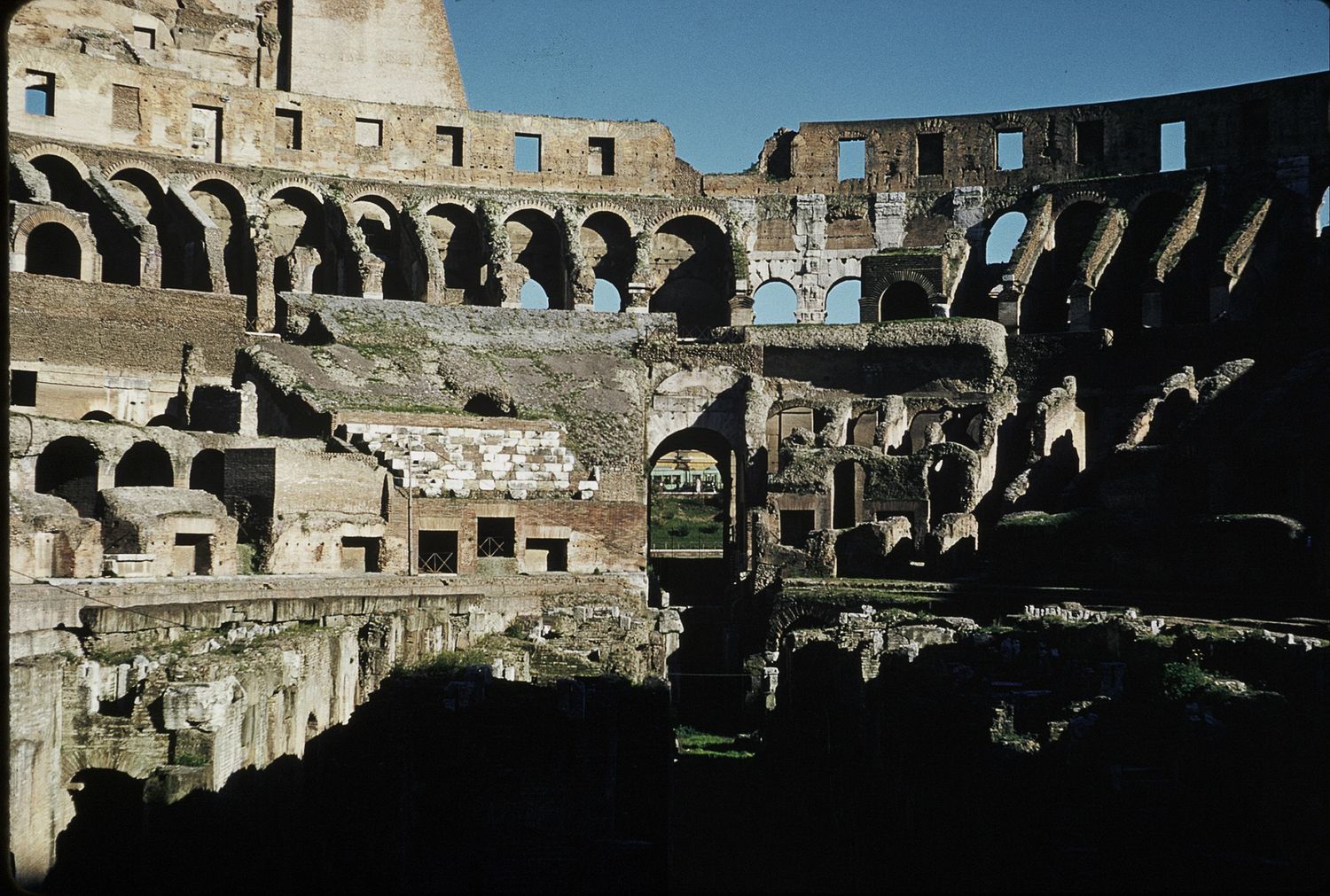 Interior ruins of the ancient Roman Colosseum showing arched walls and underground hypogeum.