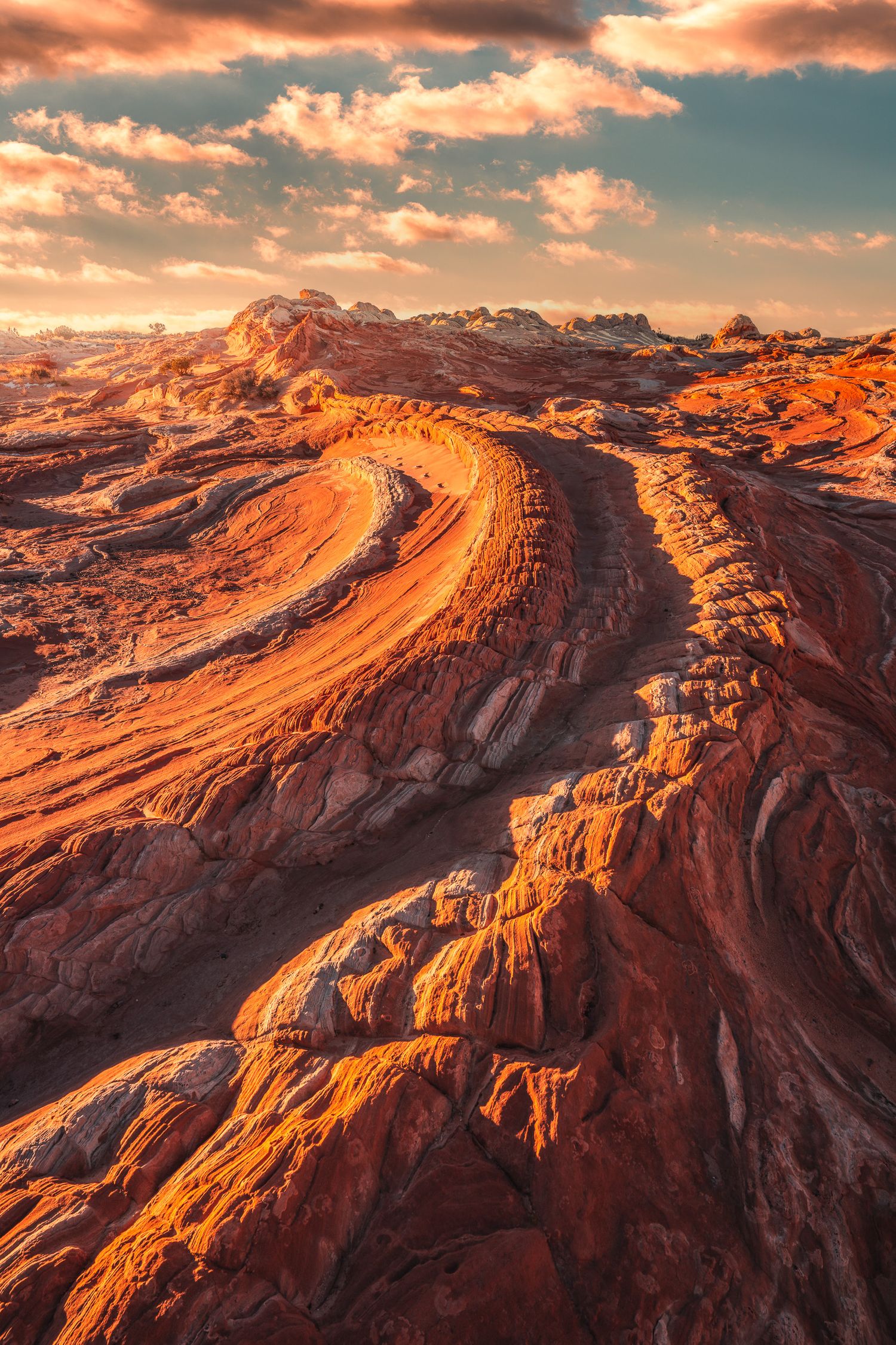 Swirling red and orange sandstone rock formations with wavy erosion patterns glowing at golden hour sunset.