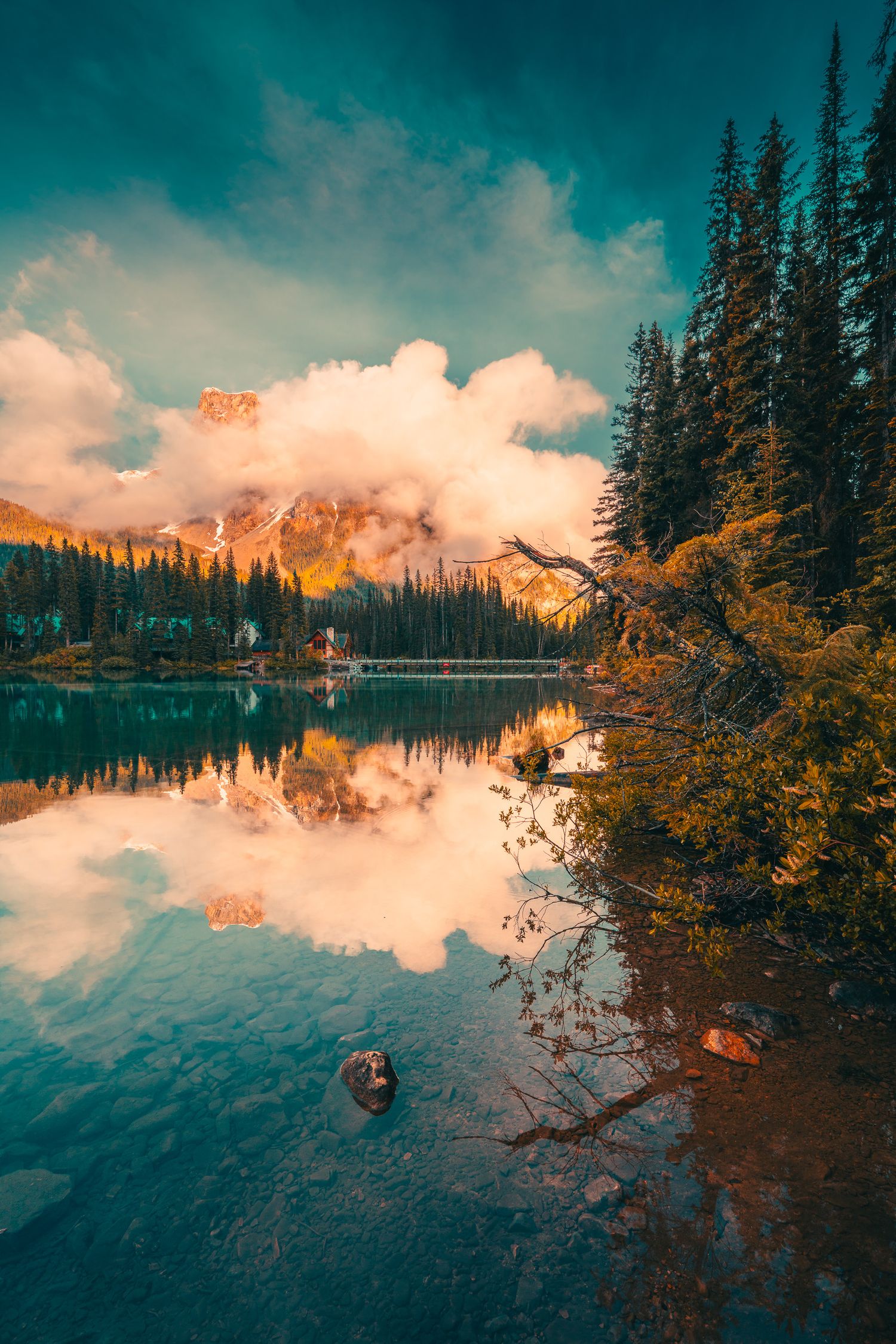 Peaceful mountain lake reflecting dramatic clouds and pine forest at golden hour.
