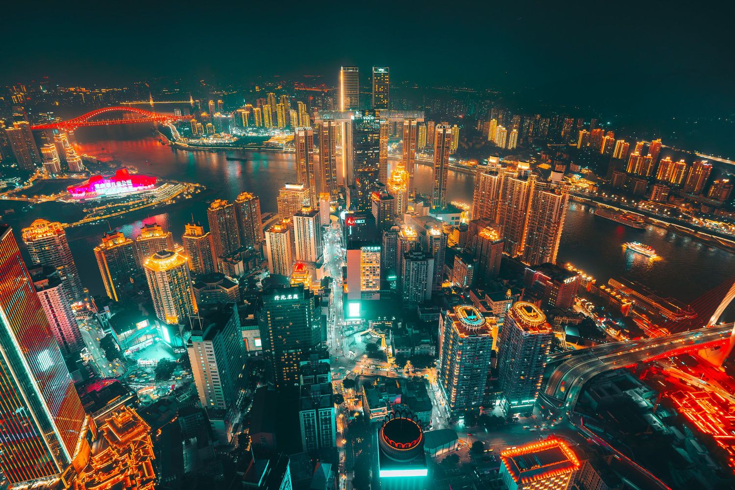 Breathtaking aerial night view of Chongqing's glowing cityscape with colorful neon lights along the Yangtze River.