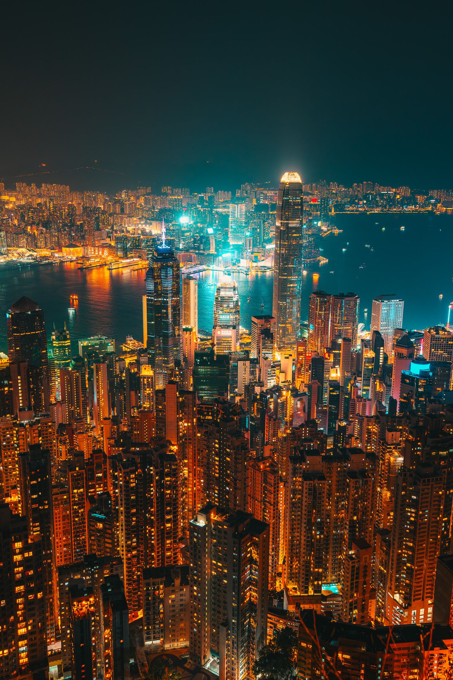 Stunning aerial night view of Hong Kong skyline blazing with colorful city lights over the harbor.