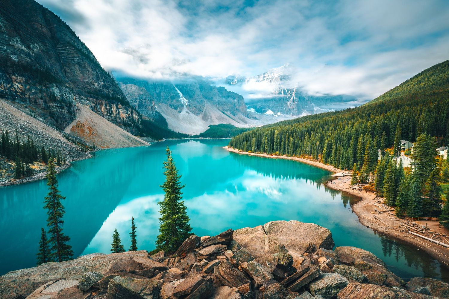 Turquoise glacial Moraine Lake reflecting mountains and pine trees in Banff National Park, Canada.