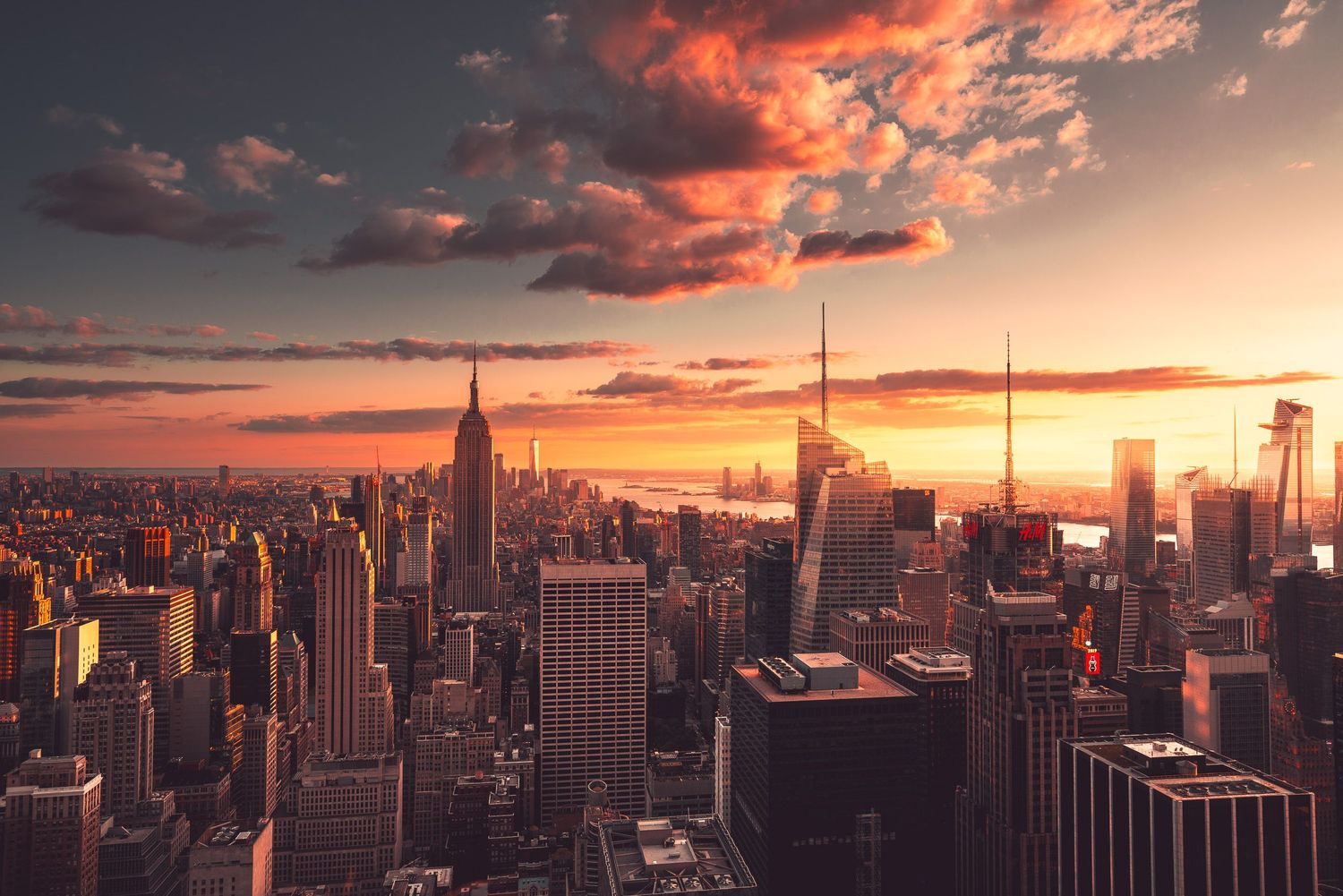 New York City skyline at golden sunset with Empire State Building and dramatic red clouds.
