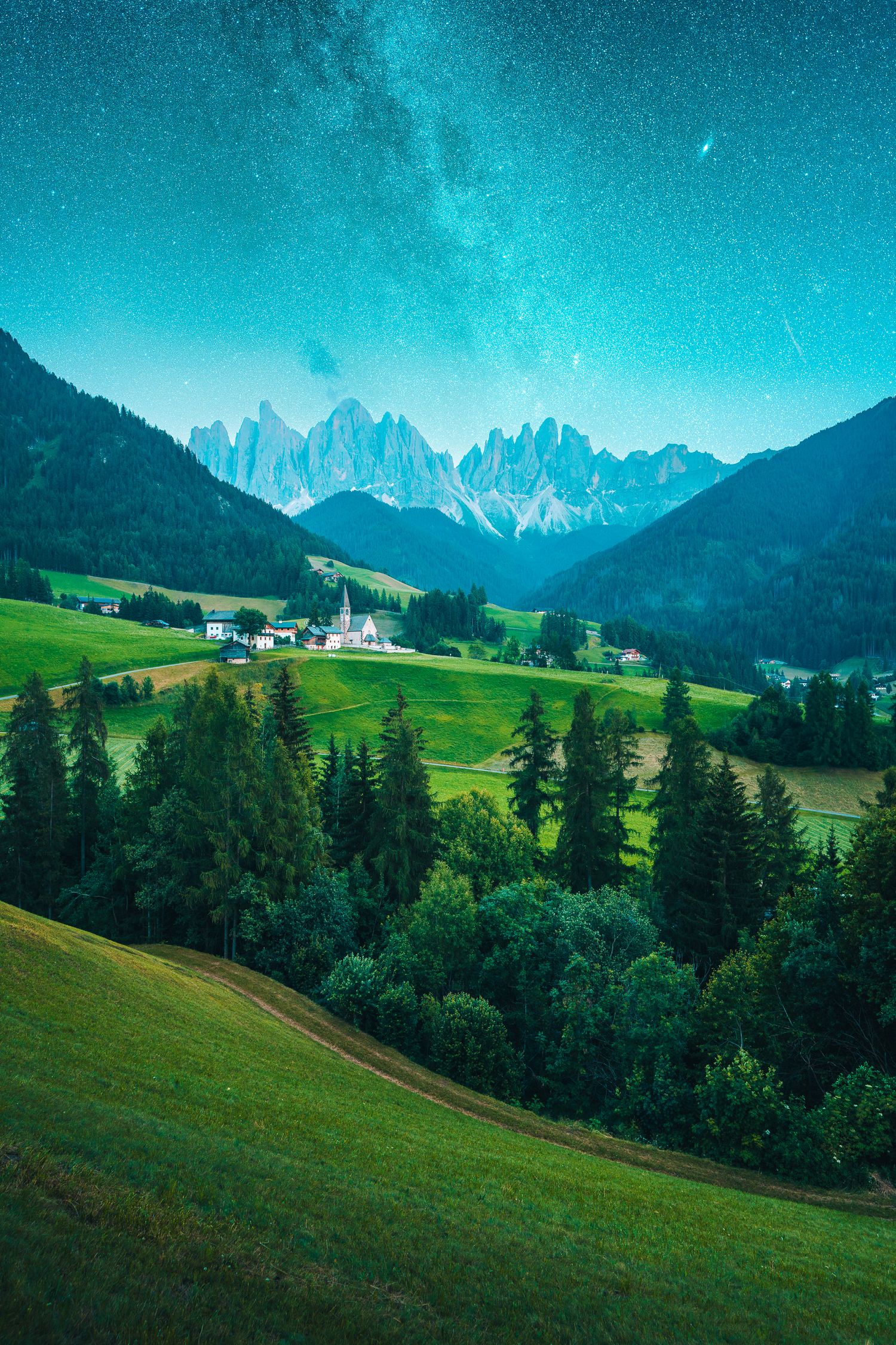 Aerial view of a charming alpine village nestled in lush green valleys beneath jagged Dolomite peaks under a starry sky.
