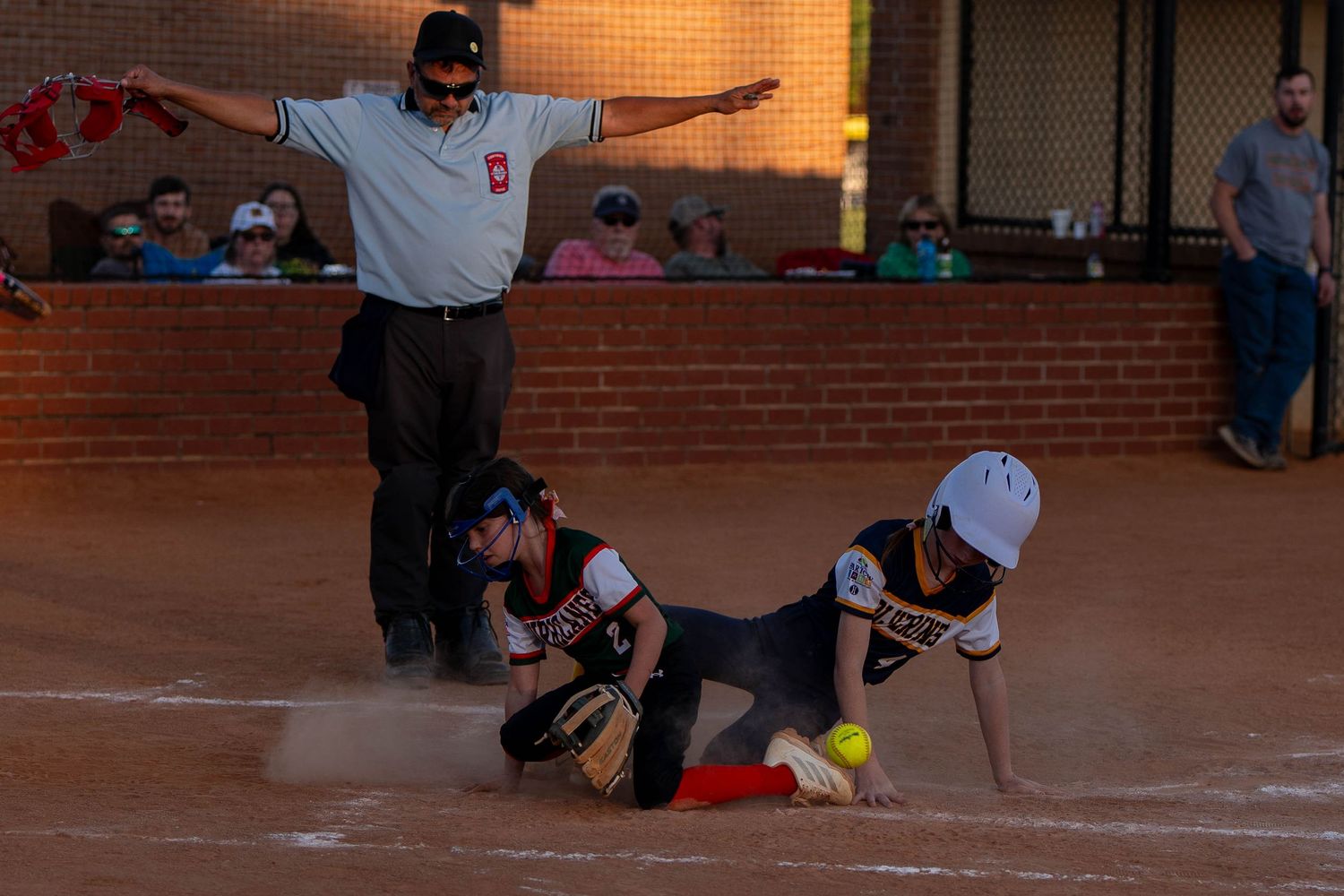 Youth softball game action at home plate during a close scoring play
