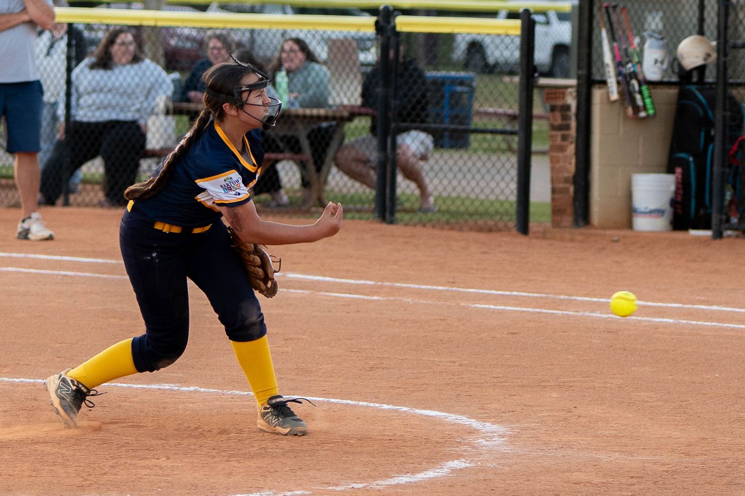Youth softball pitcher delivering a pitch during game action