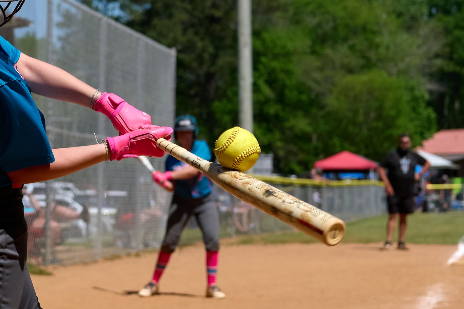 Close-up softball action photo showing bat-to-ball contact during a game