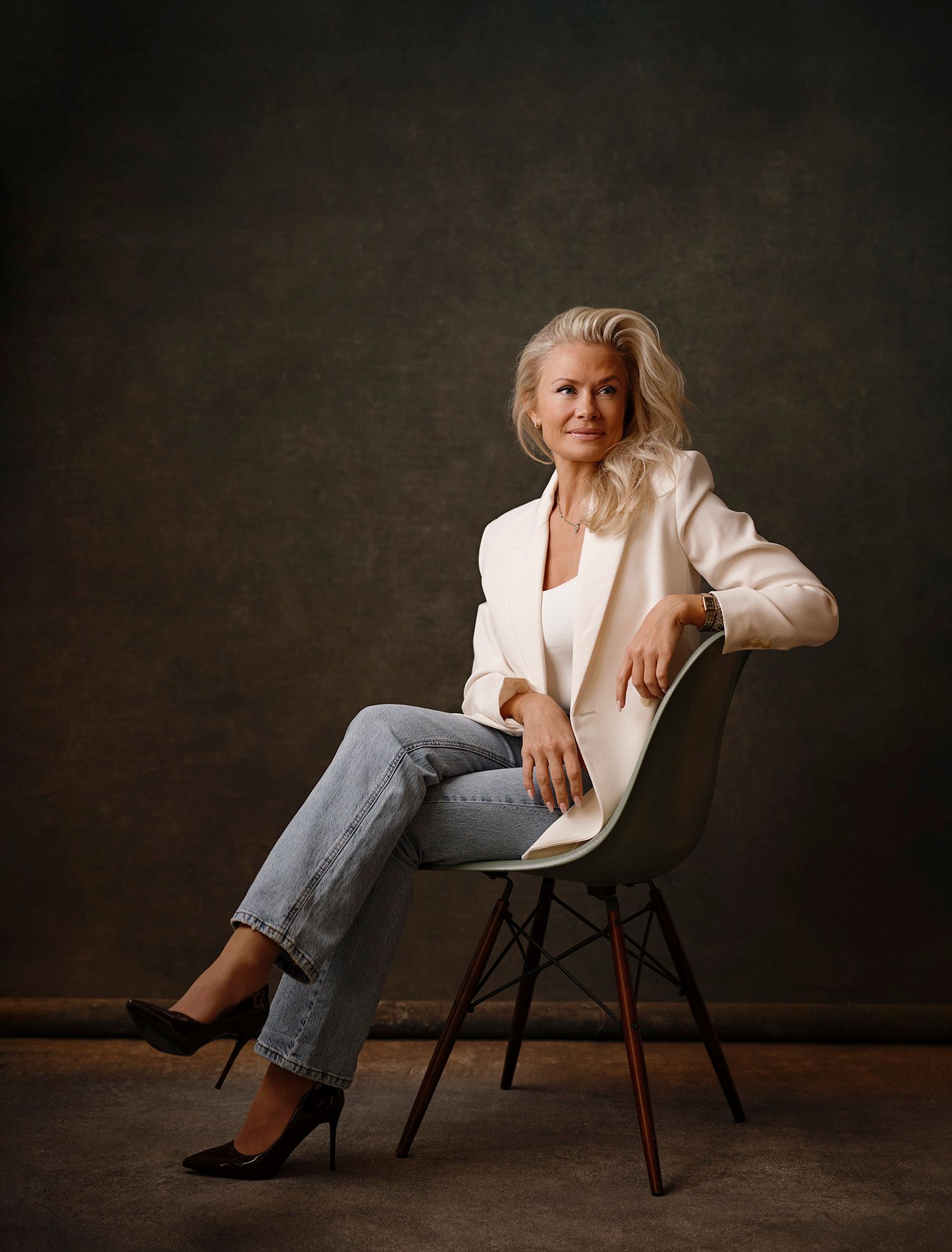 Elegant woman with white hair seated in modern chair.