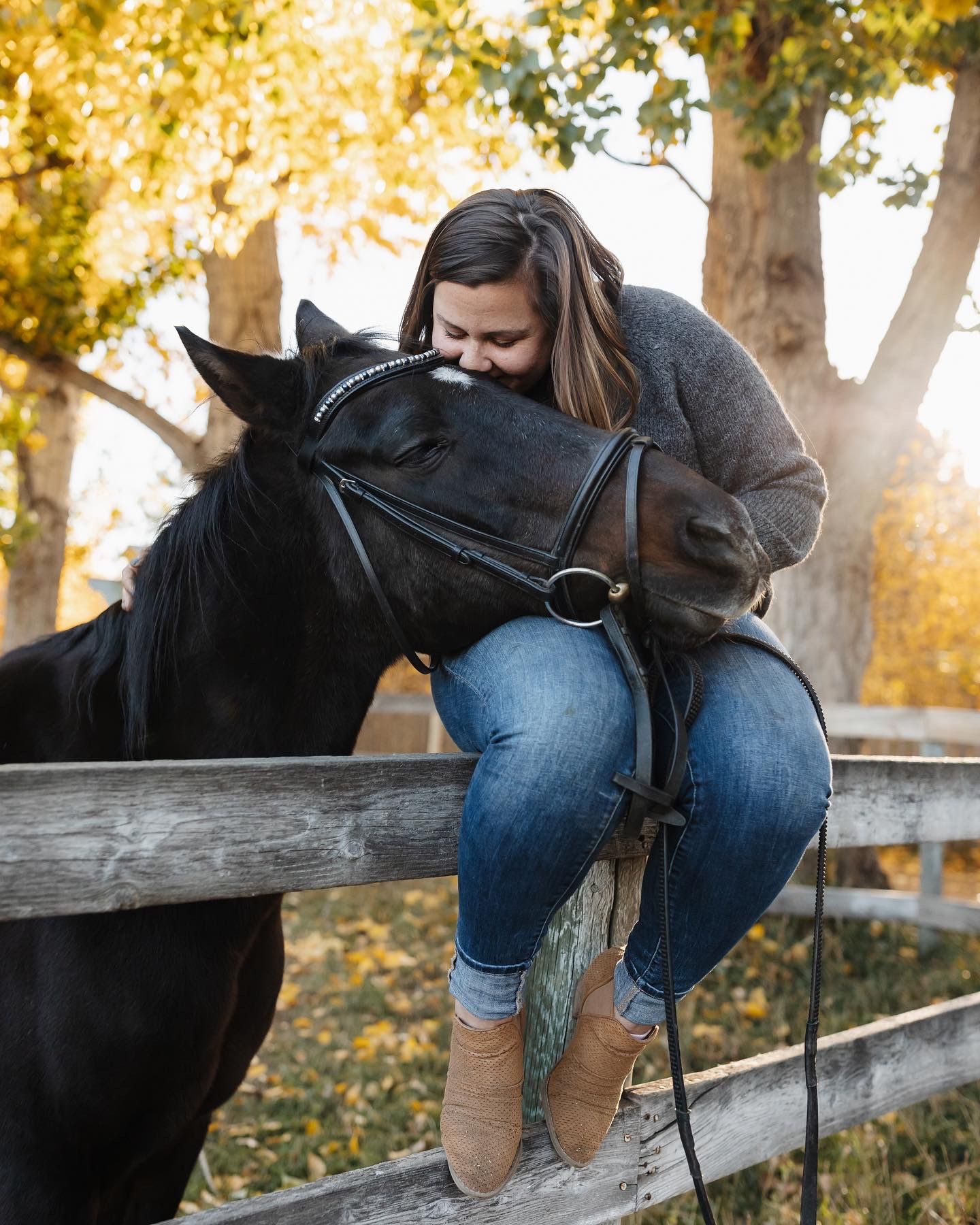 A girl and her horse pose for a picture while sitting on a fence.