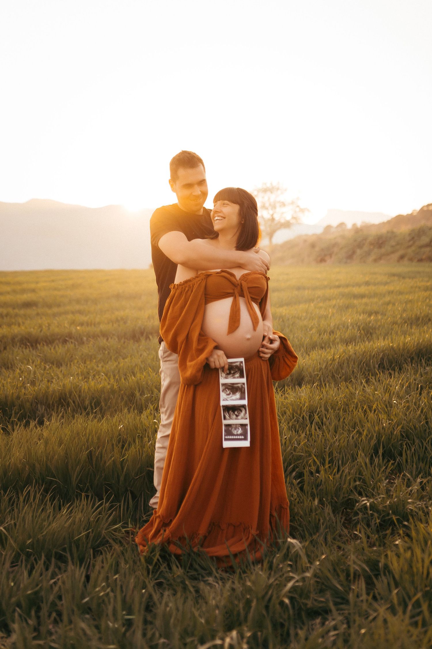 Padres abrazando a su hija durante una sesión de fotografía familiar al atardecer.