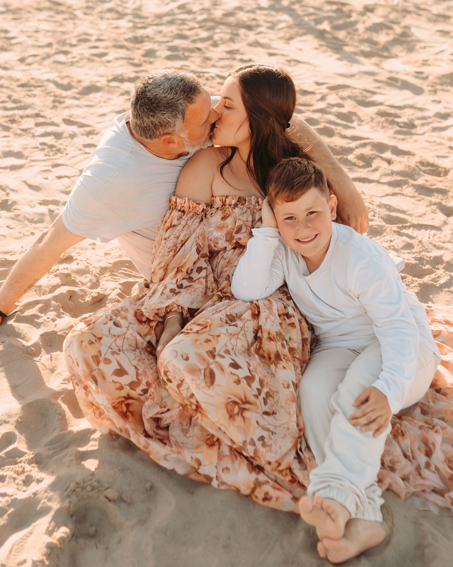 Familia disfrutando de una sesión de fotografía familiar en la playa al atardecer.
