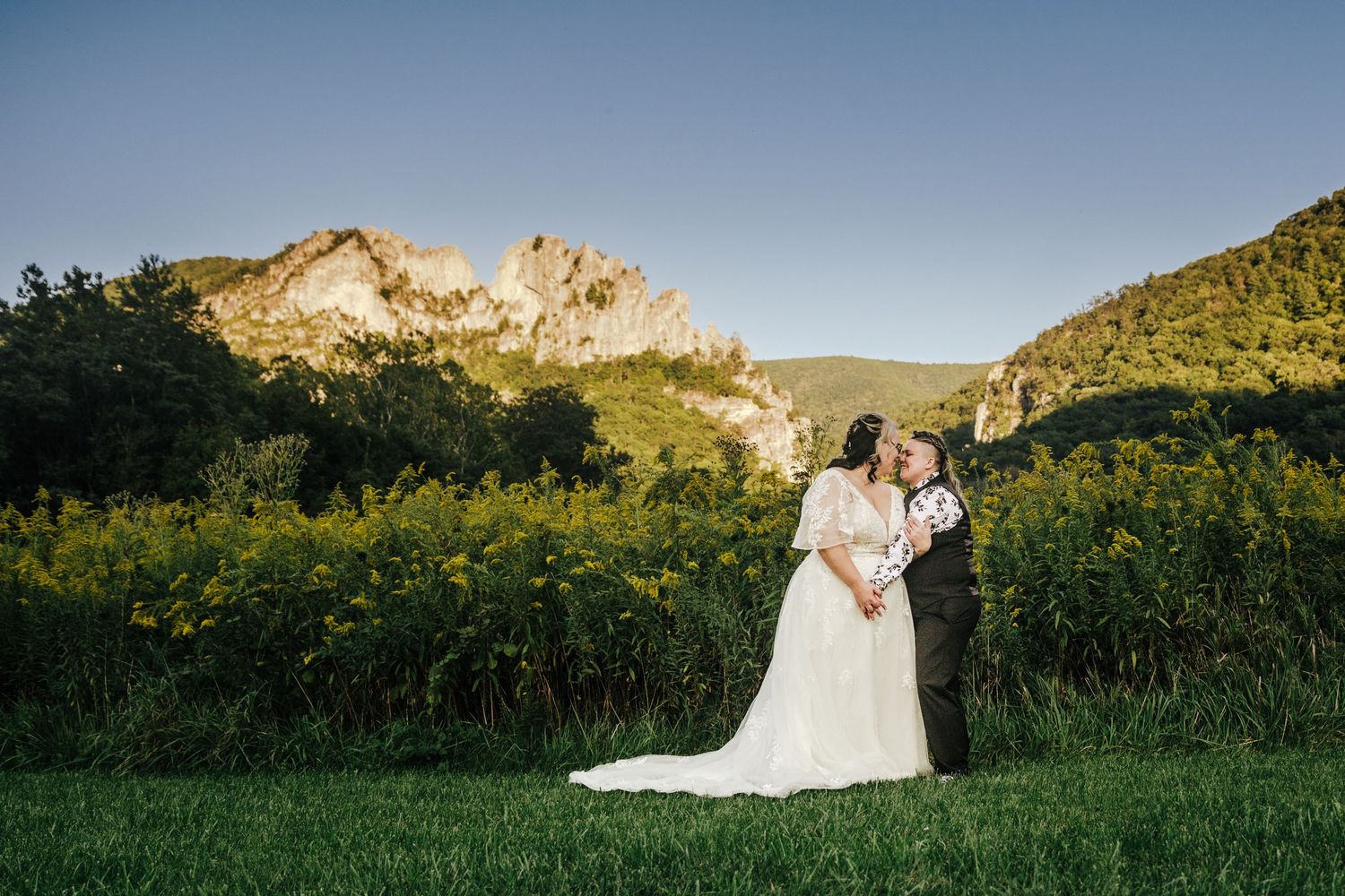 Lesbian brides pose in the field with Seneca Rocks in the background. Elopement photographer at Seneca Rocks