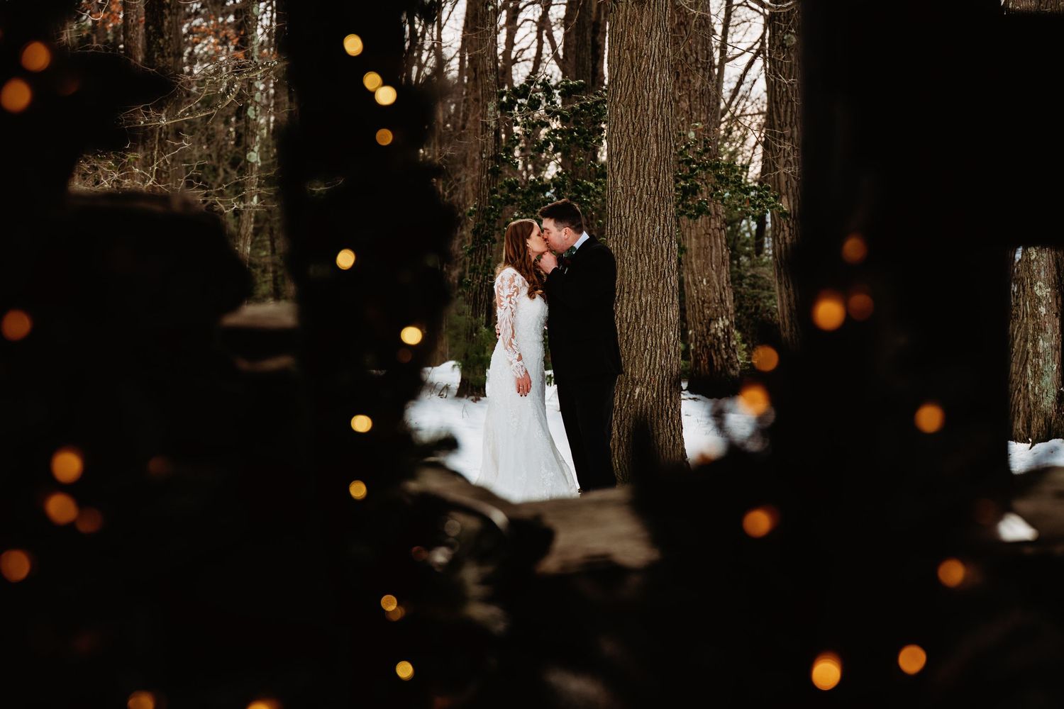 Bride and Groom embrace the cold snowy atmosphere of a January day at Coopers Rock State Forest, WV. Christmas lights fill the foreground.