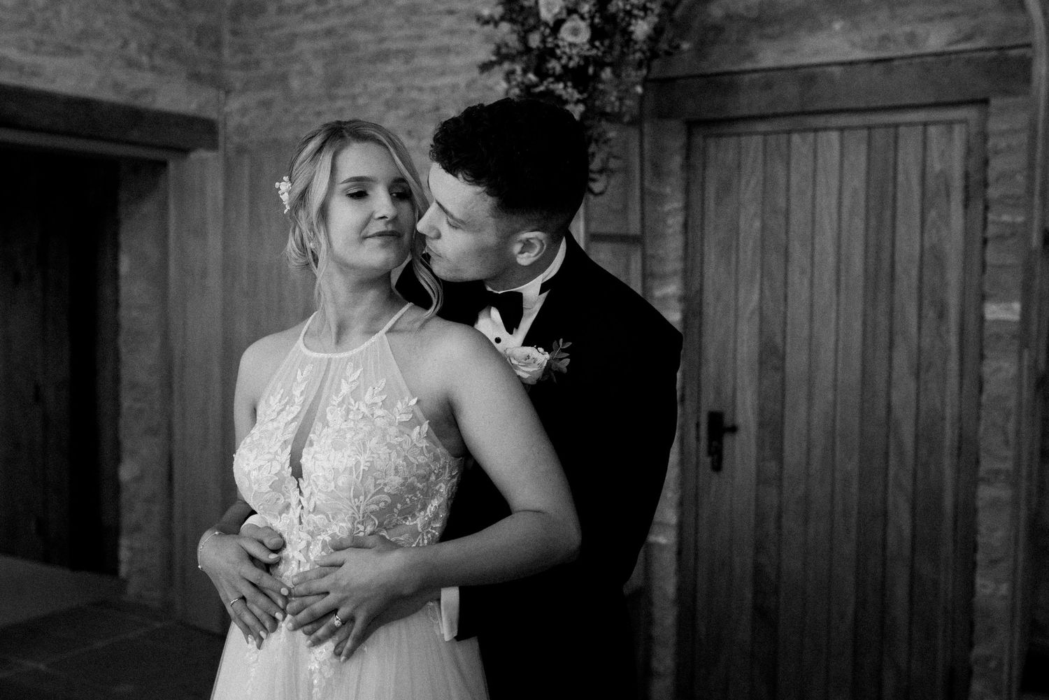 A romantic black and white wedding moment showing a couple embracing in an intimate rustic setting.