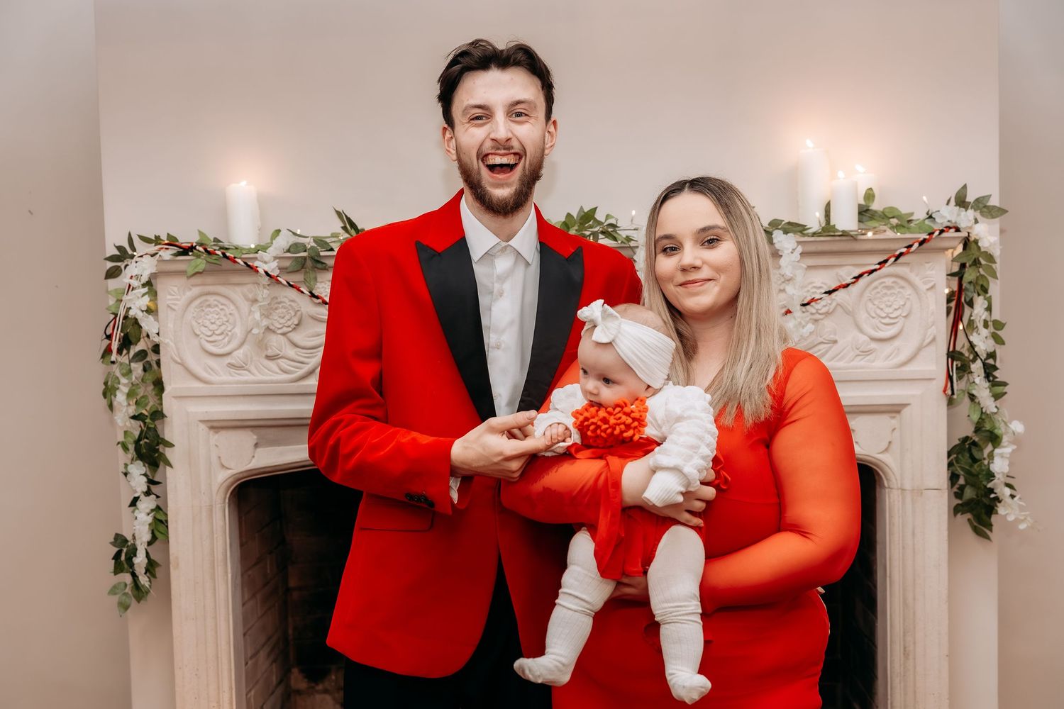 A couple in matching red and white holiday outfits poses for a series of festive photos with their small dog.