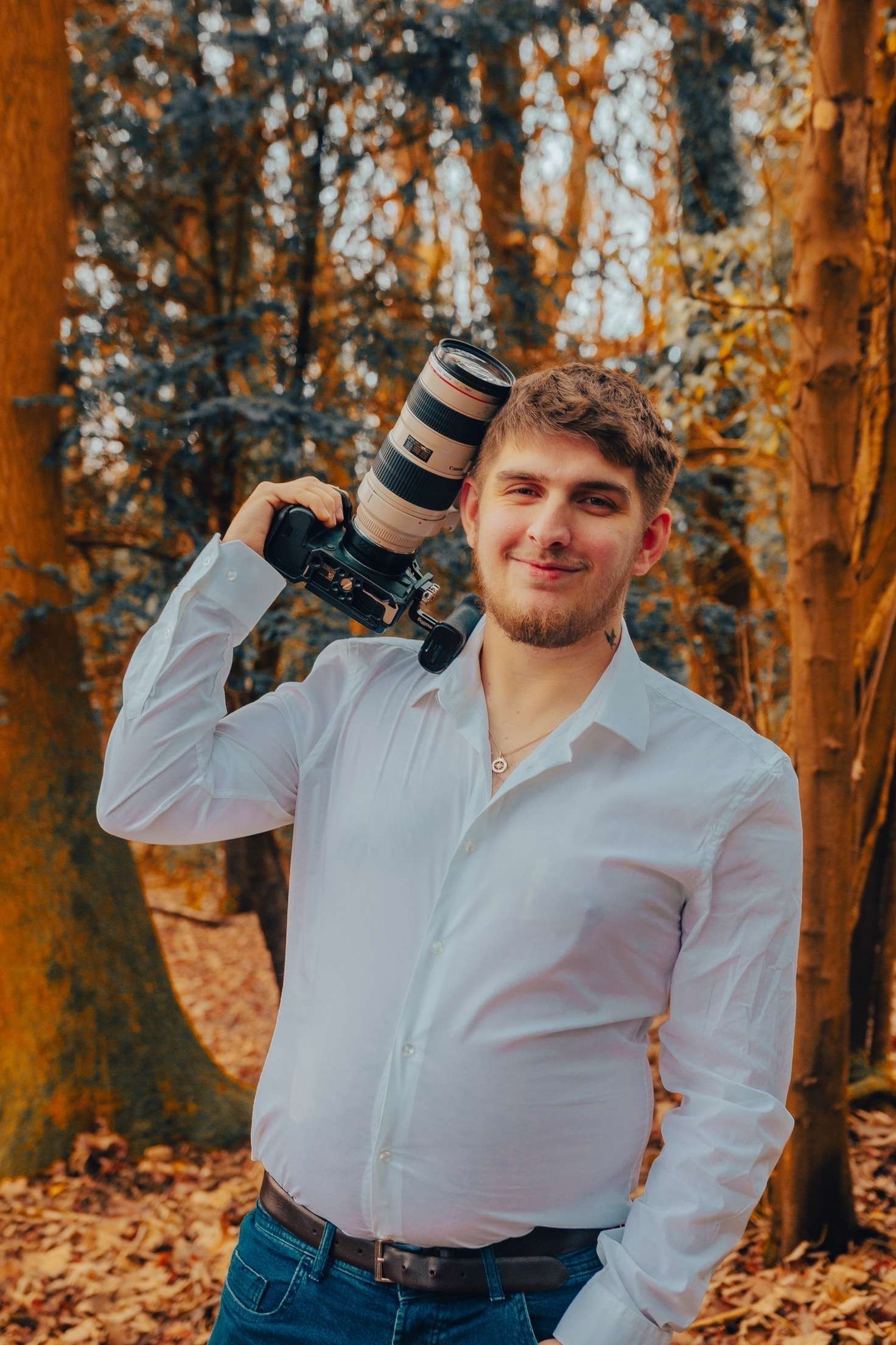 Professional photographer showcasing camera equipment in autumn forest.