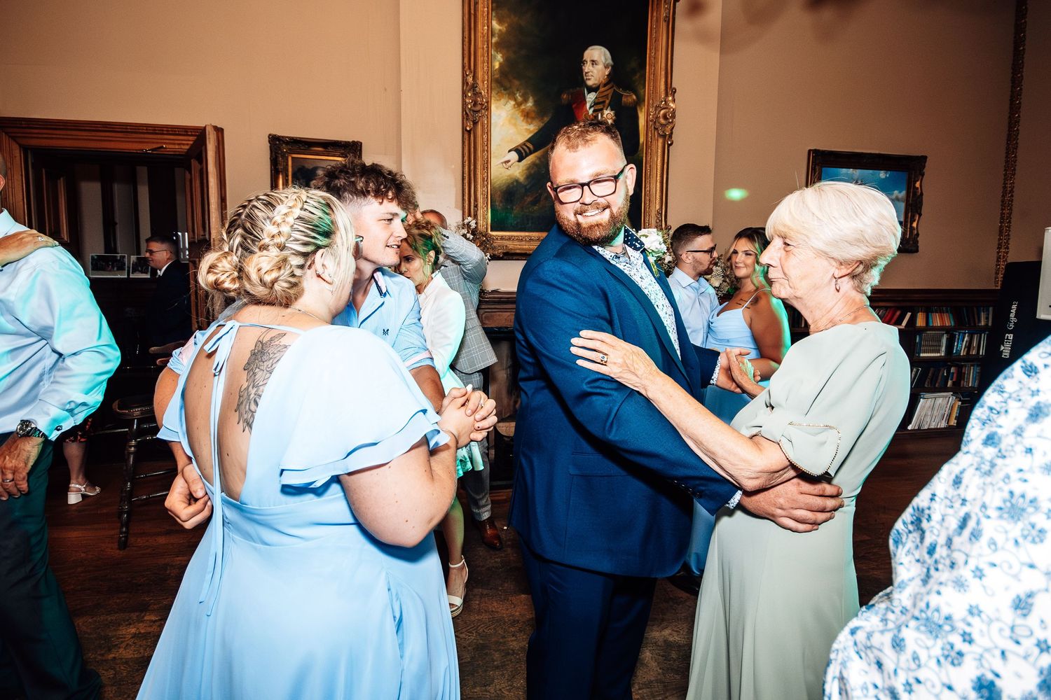 People dancing together at a wedding reception in a warm-lit indoor venue.