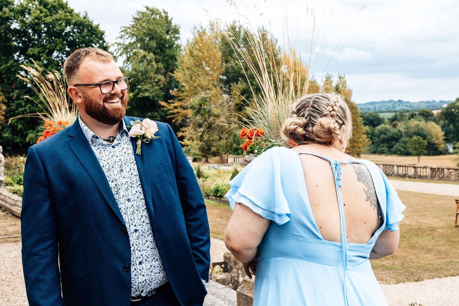 A couple shares an intimate moment outdoors with a scenic natural landscape and trees in the background.