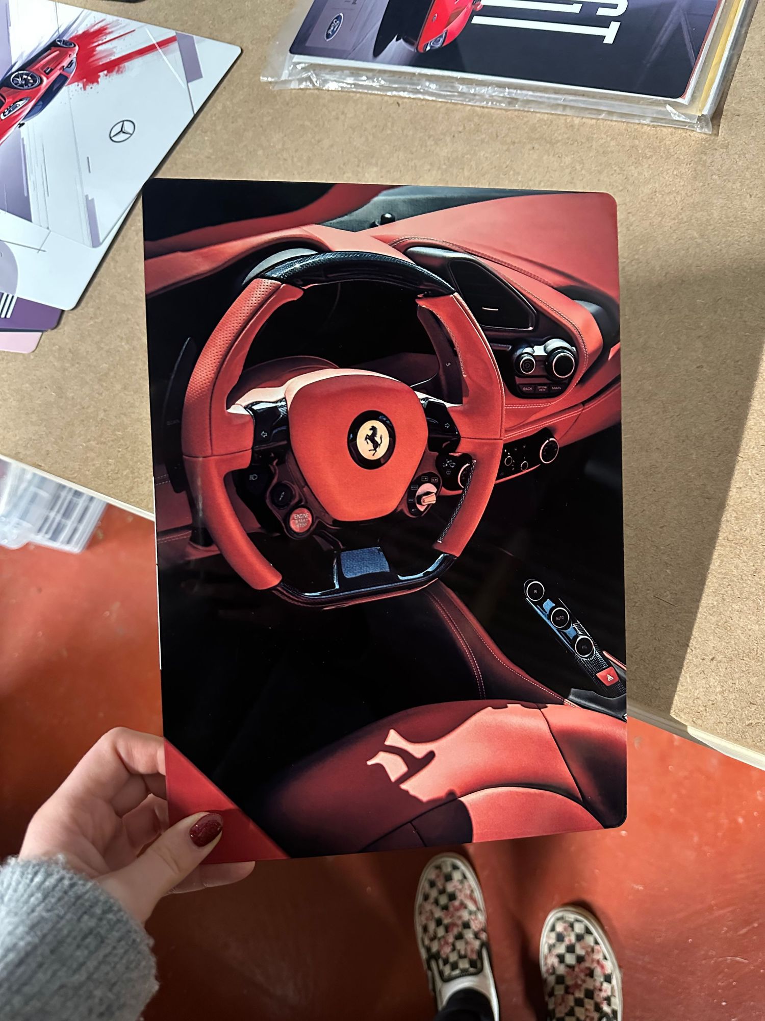 Interior view of a red Ferrari cockpit showing the steering wheel and digital instrument cluster from multiple angles.
