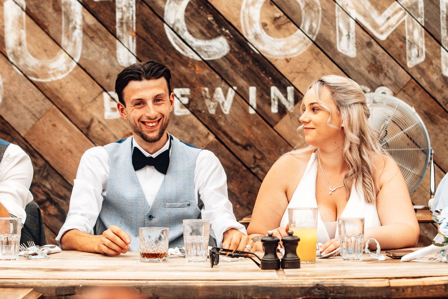 Group of people dining together at a rustic wooden table in a restaurant setting.